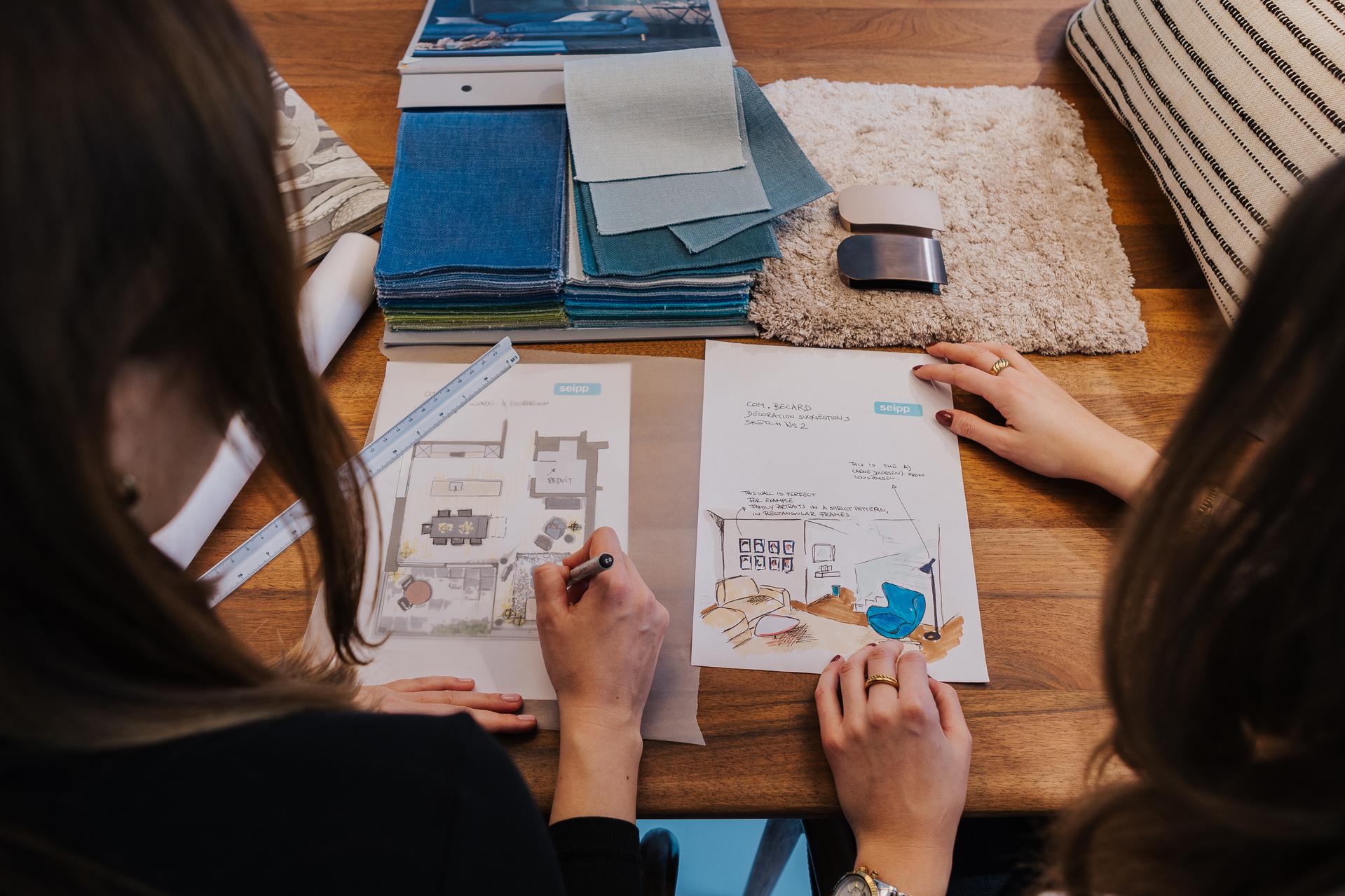 Zwei Personen bei der Planung eines Einrichtungskonzepts mit Materialmustern und Grundriss