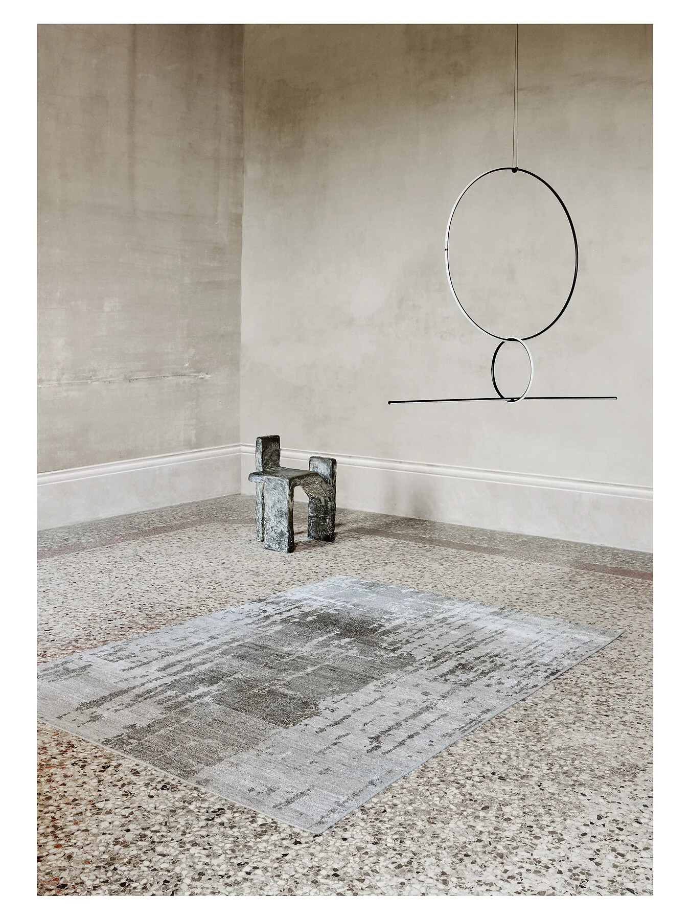 Heller Teppich auf Steinterrasse mit skulpturalem Möbelobjekt