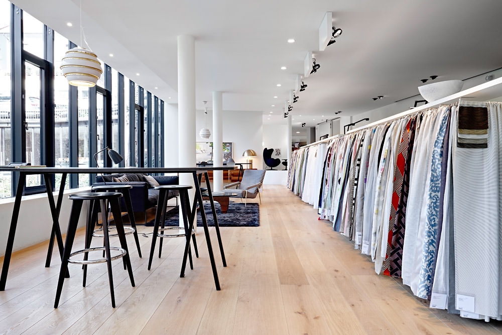 Textilabteilung in der Ausstellung von Seipp Wohnen in Waldshut mit Stoffbahnen, Barhockern und großen Fenstern.