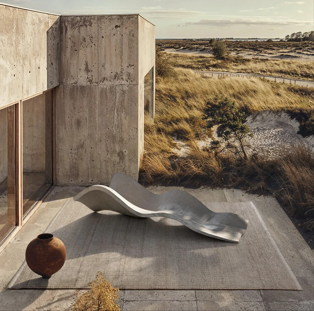 Grauer Outdoor-Teppich auf Terrasse mit Betonwänden und skulpturaler Liege