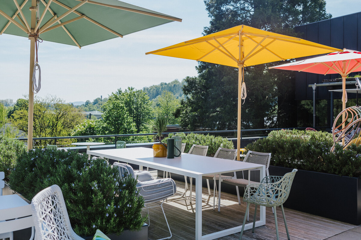 Ausstellung auf der Dachterrasse in Tiengen mit weißem Gartentisch, modernen Stühlen und Sonnenschirmen