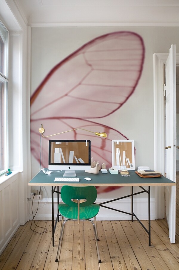 Wandtapete mit übergroßem transparentem Flügelmotiv hinter einem Schreibtisch