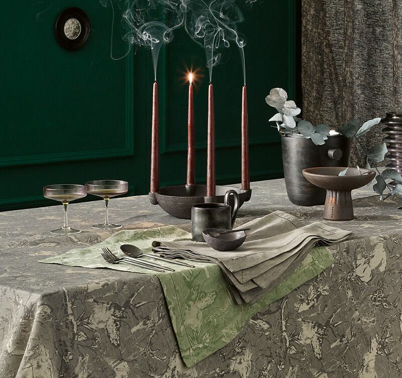 Tisch mit grüner Damwild Tischwäsche, Kerzen und Gläsern