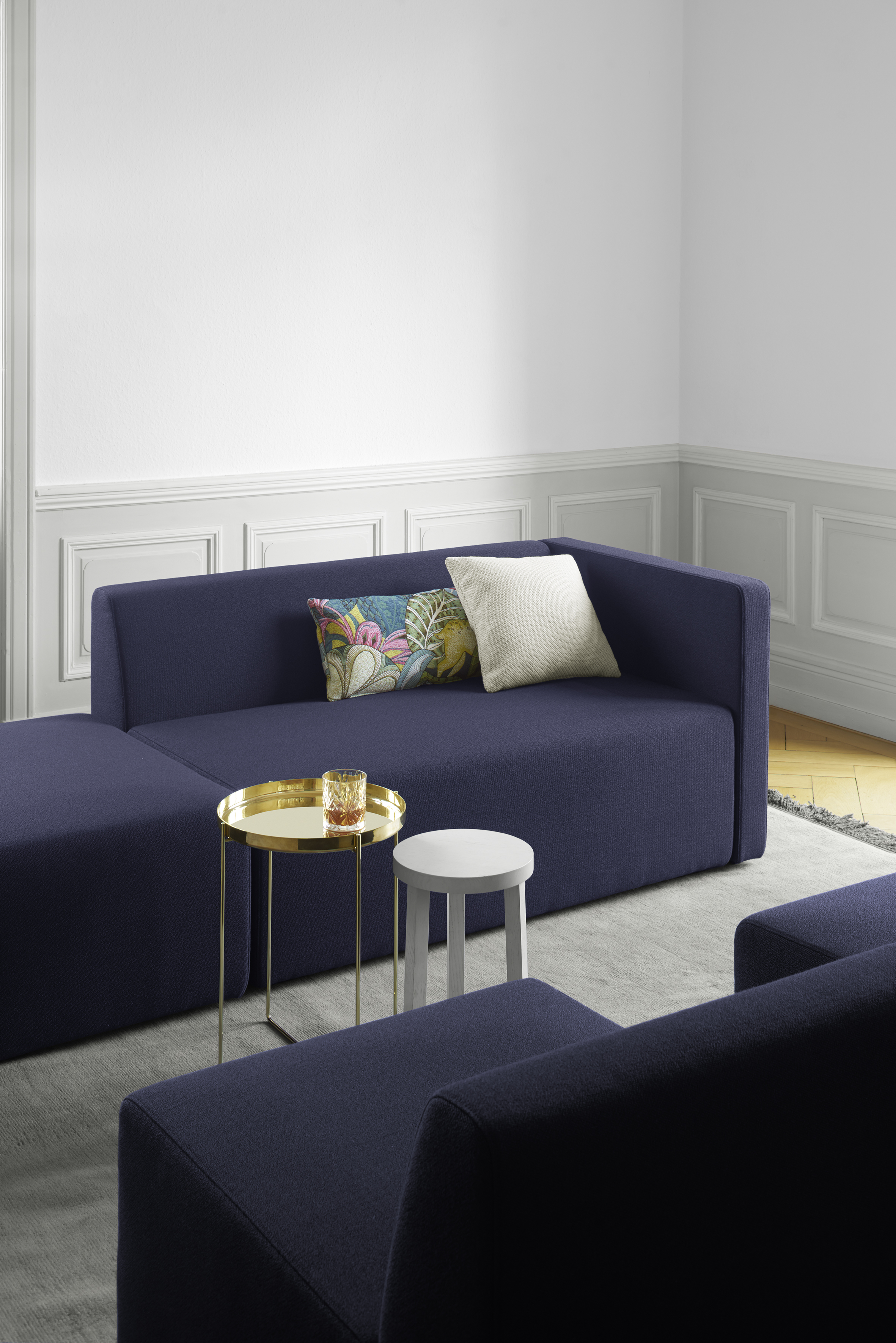 goldener Beistelltisch Habibi mit weißem Hocker vor blauem Sofa