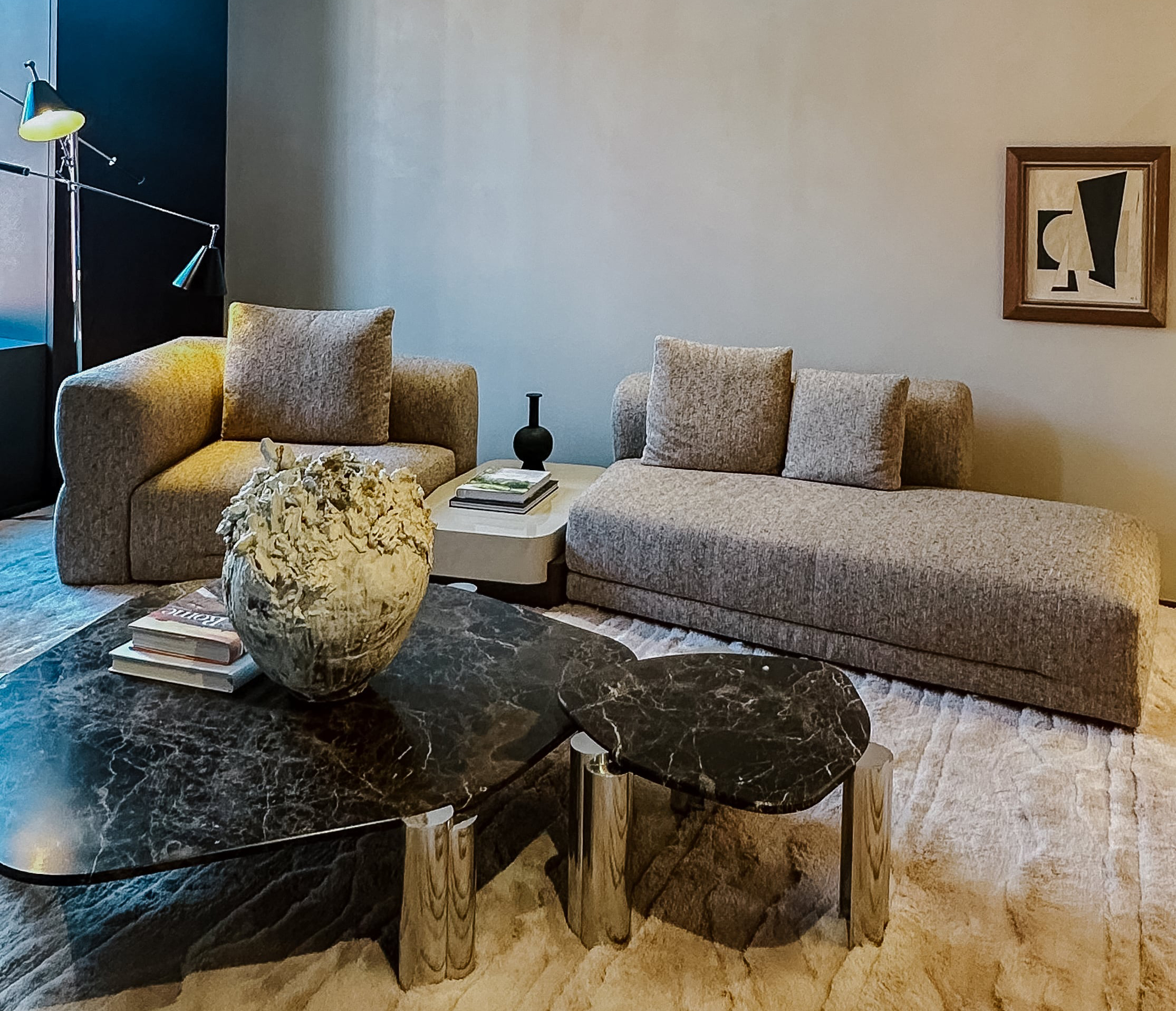 Skulpturales Sofa-Ensemble von Molteni&C. mit zurückhaltender Textilstruktur, ergänzt durch dunkle Couchtische mit organischer Form und verchromtem Gestell. Die Szene strahlt französische Eleganz und wohnliche Ruhe aus.