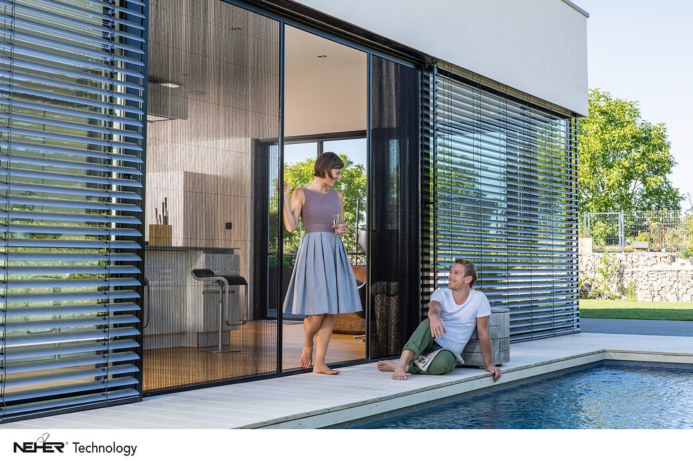 Hausfassade mit geöffneten Außenjalousien und Schiebetür zum Poolbereich