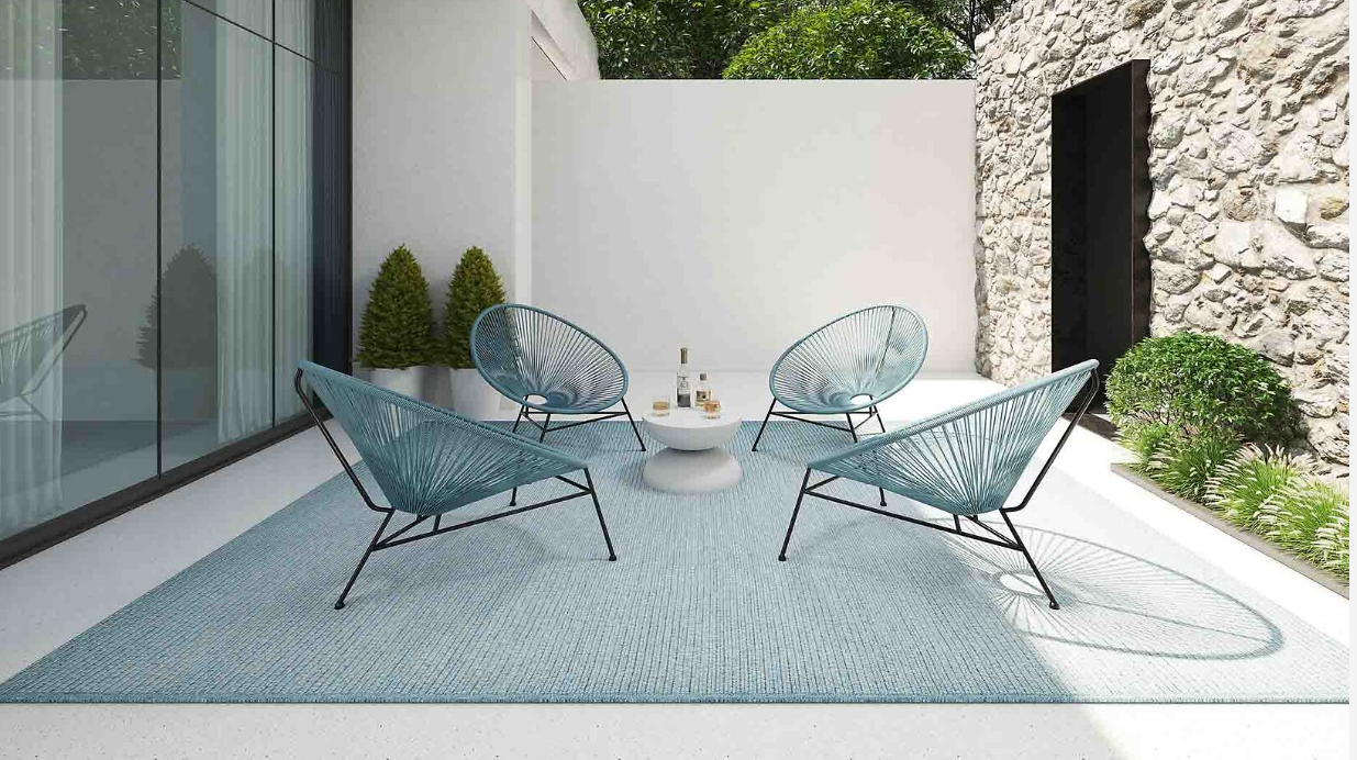 Vier türkisfarbene Lounge-Stühle auf hellblauem Outdoor-Teppich in moderner Innenhofszene