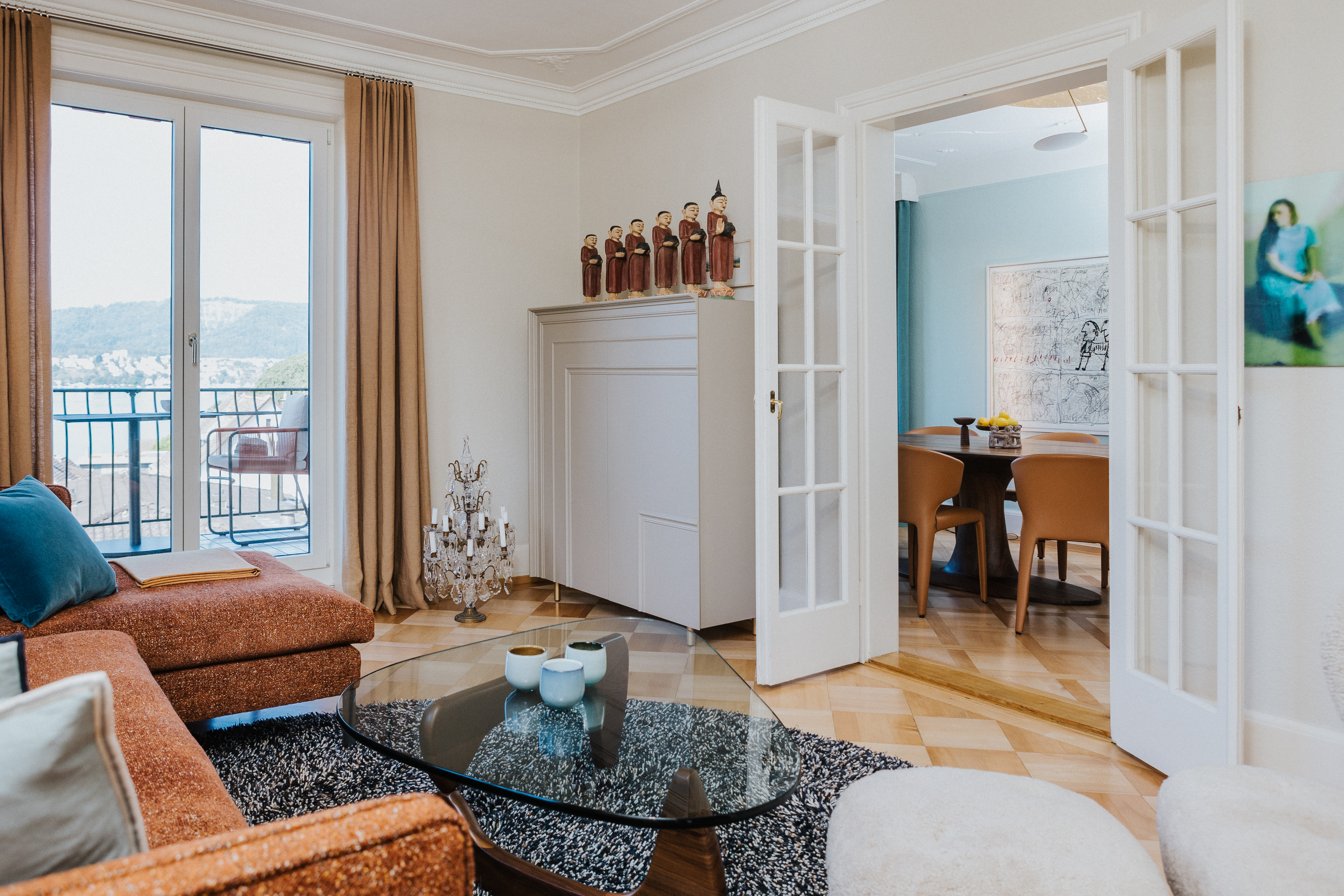 Wohnzimmer mit orientalischem Flair, Blick in Esszimmer mit Wand in Türkisblau und Kunst an der Wand.