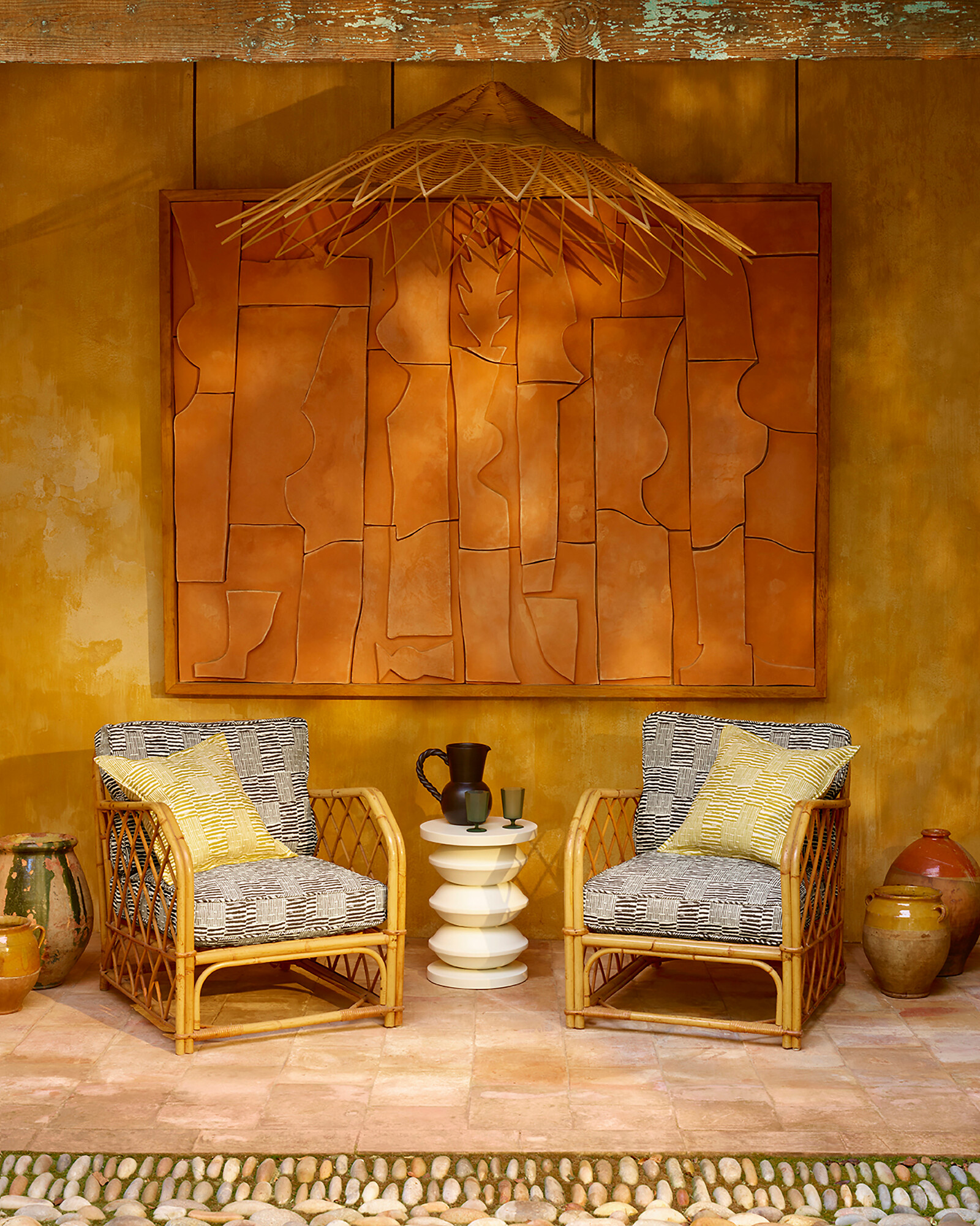 Rattanstühle vor goldfarbener Wand mit strukturierter Holzarbeit