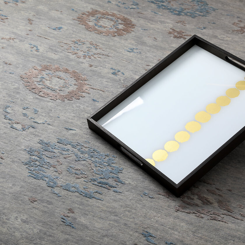 Grau-blauer Teppich mit feinen Ornamenten und Tablett mit Glasplatte