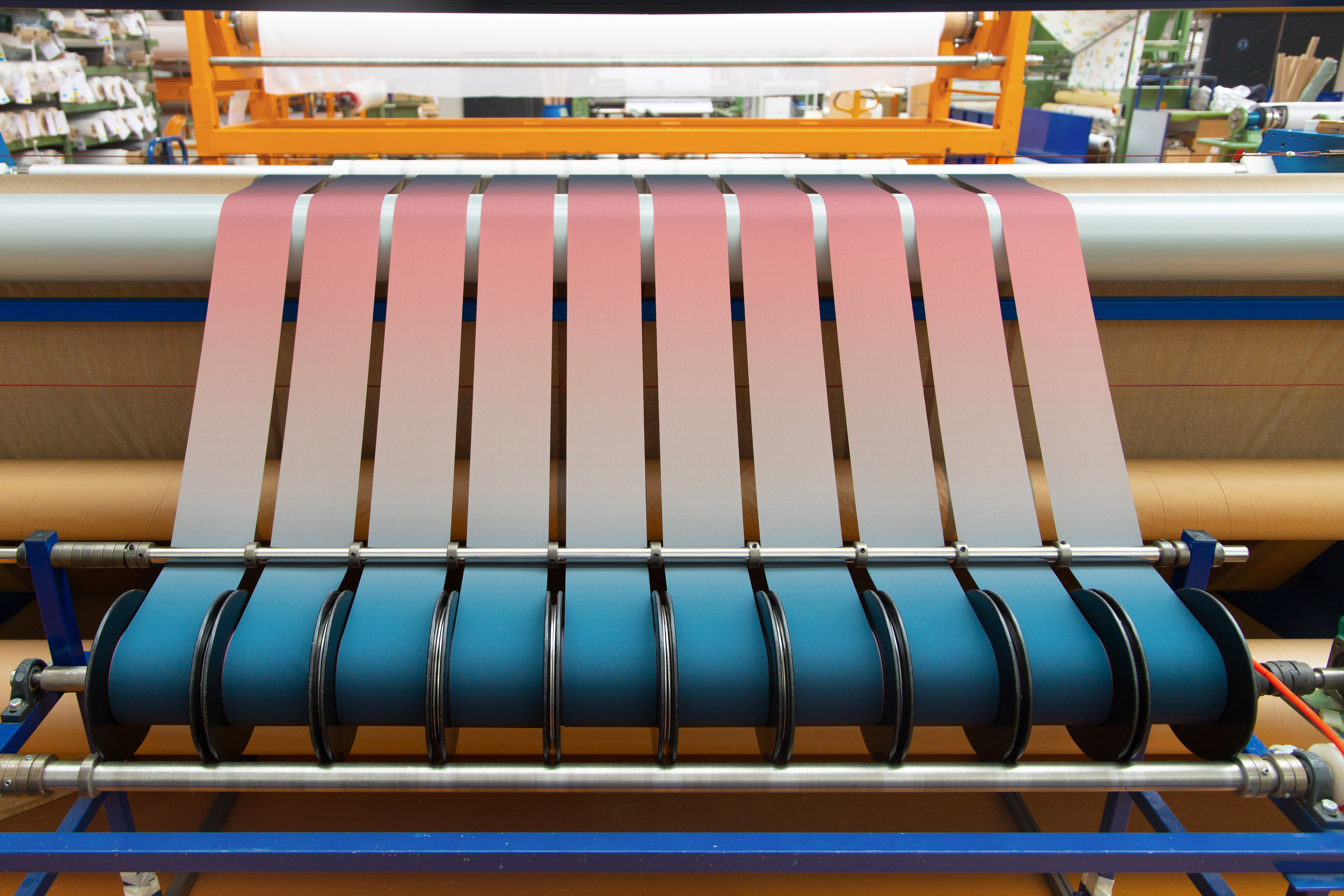 Maschine mit textilen Lamellen in Farbverlauf von Rosa zu Blau in der Produktion von Stoffbahnen