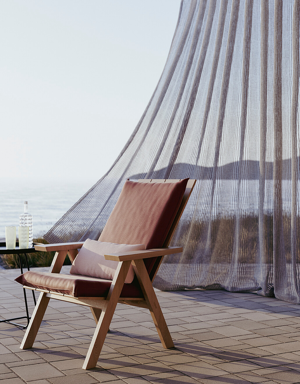 Outdoor-Vorhang weht im Wind hinter einem Loungesessel mit rotem Lederpolster