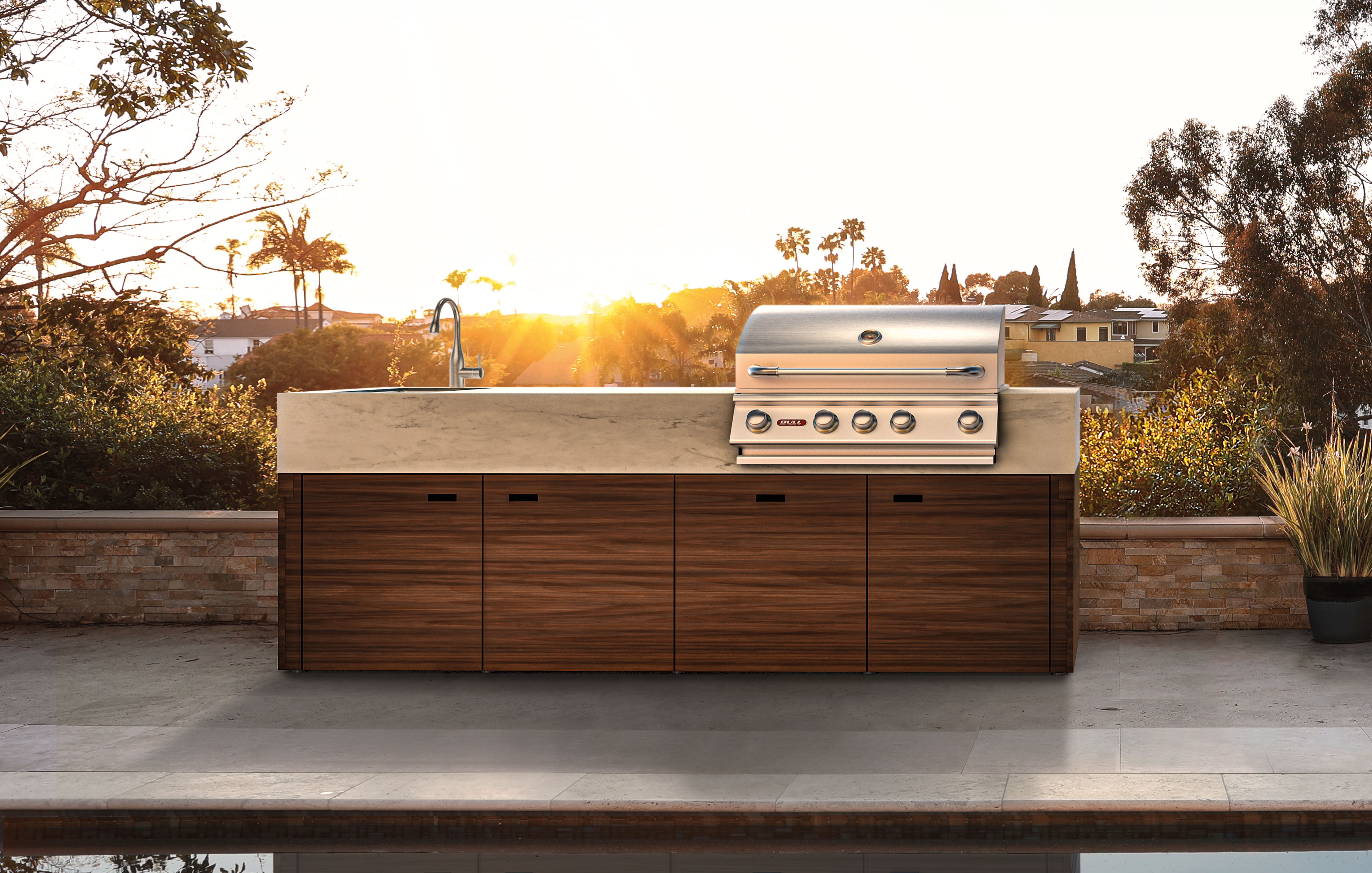 Freistehende Outdoor-Küche mit Holzfronten, Spüle und Grill bei Sonnenuntergang