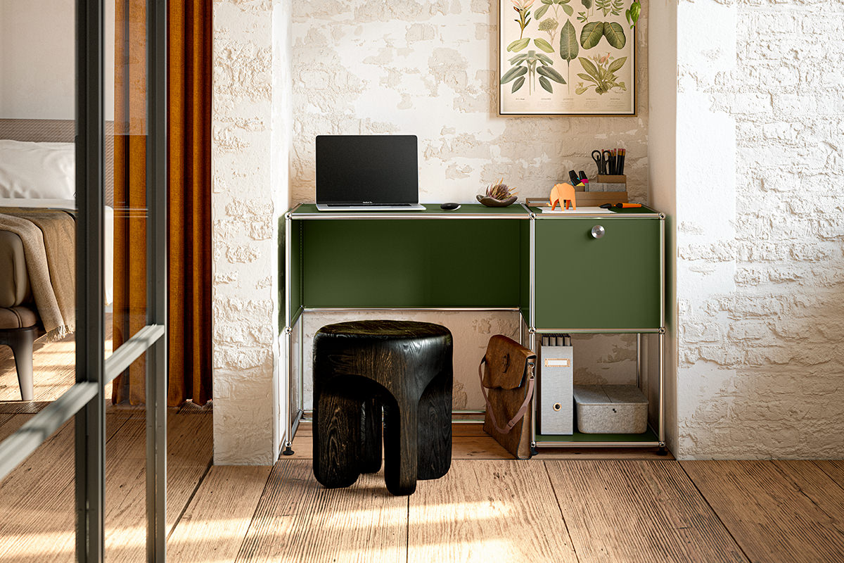 Ein kompaktes Homeoffice mit einem olivgrünen USM Haller Schreibtisch integriert sich nahtlos. Die modulare USM Einheit bietet sowohl Arbeitsfläche als auch Stauraum, ergänzt durch einen dunklen Hocker und eine Pflanzenillustration.