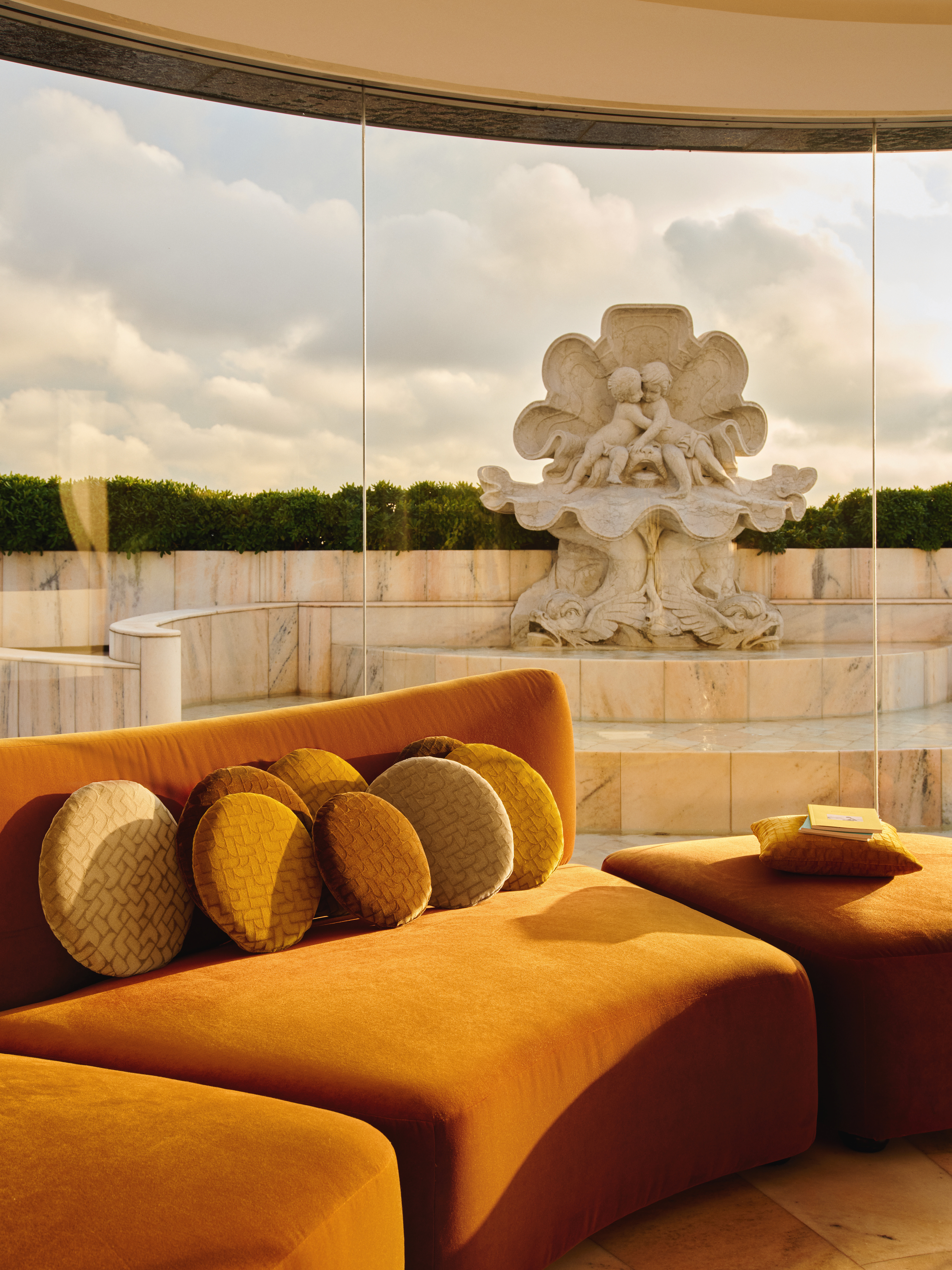 Sofa mit ockerfarbenem Bezug und runden Kissen vor großem Fenster