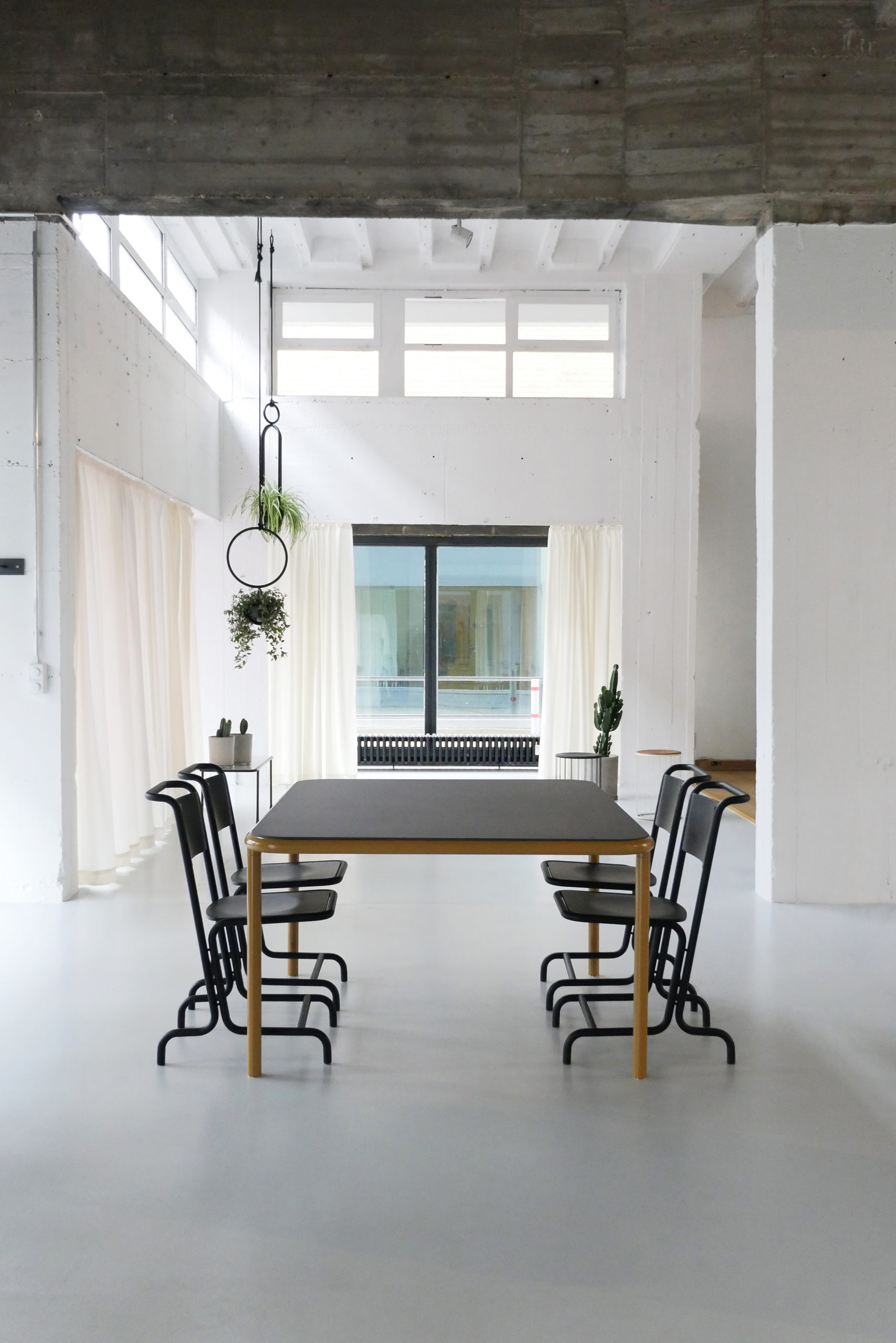 Großer rechteckiger Tisch mit hellem Holzgestell und schwarzen Stühlen