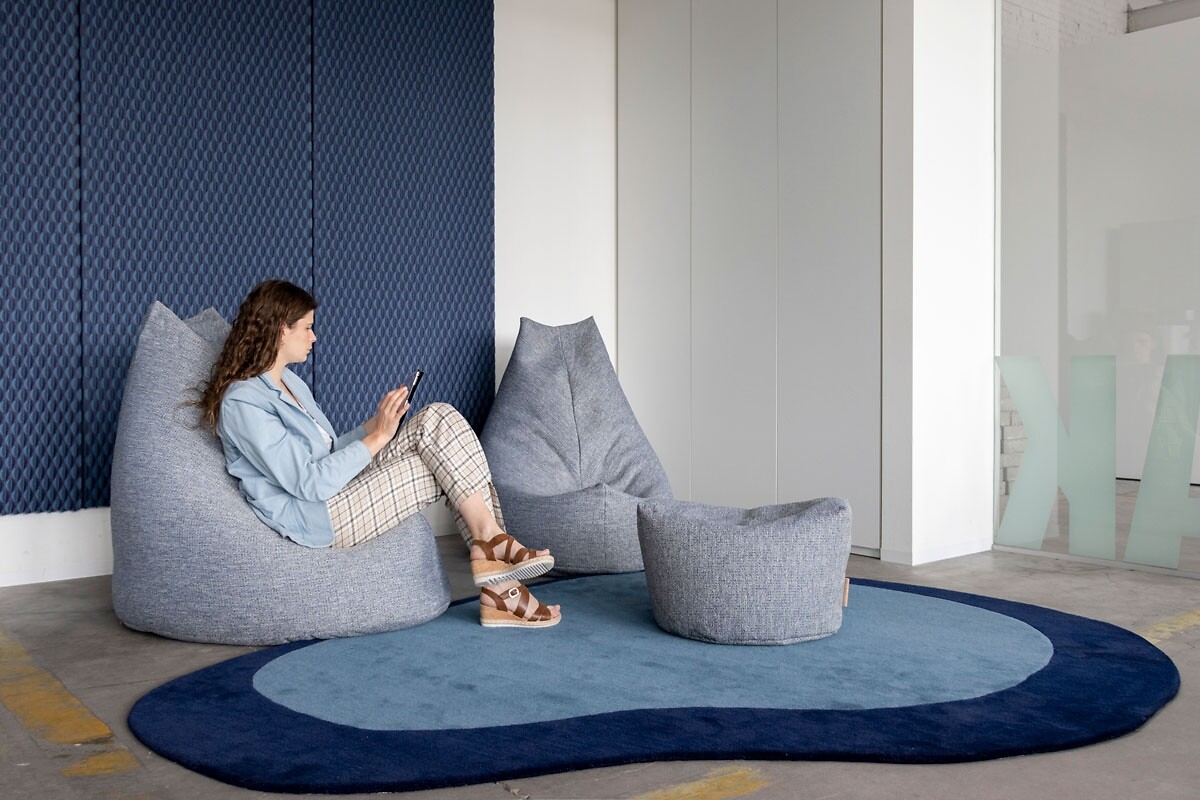 Zwei graue Sitzsäcke mit kleinem Pouf auf rundem Teppich in modernem Raum