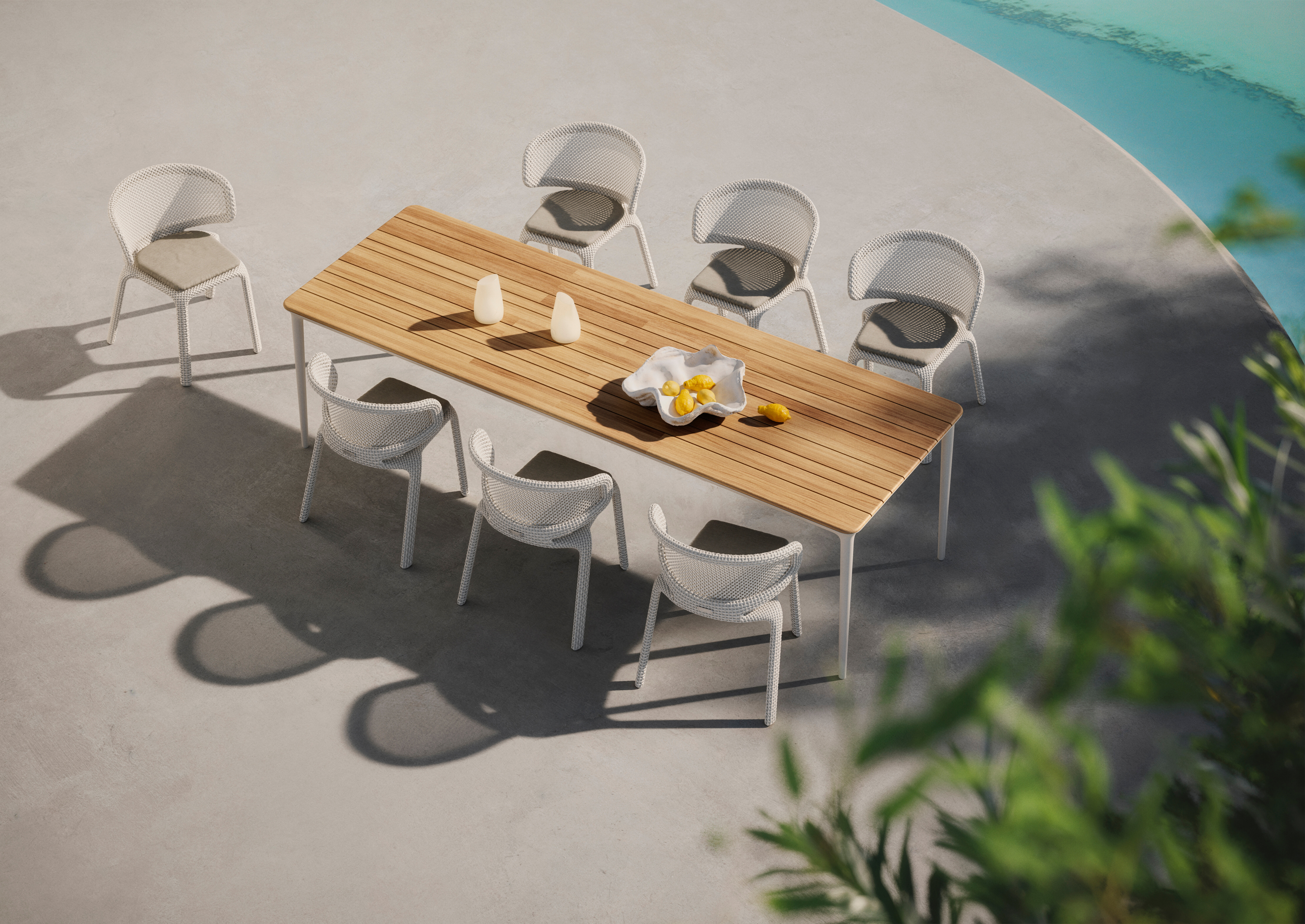 Outdoor-Esstisch aus Holz mit sieben weißen Stühlen auf heller Terrasse