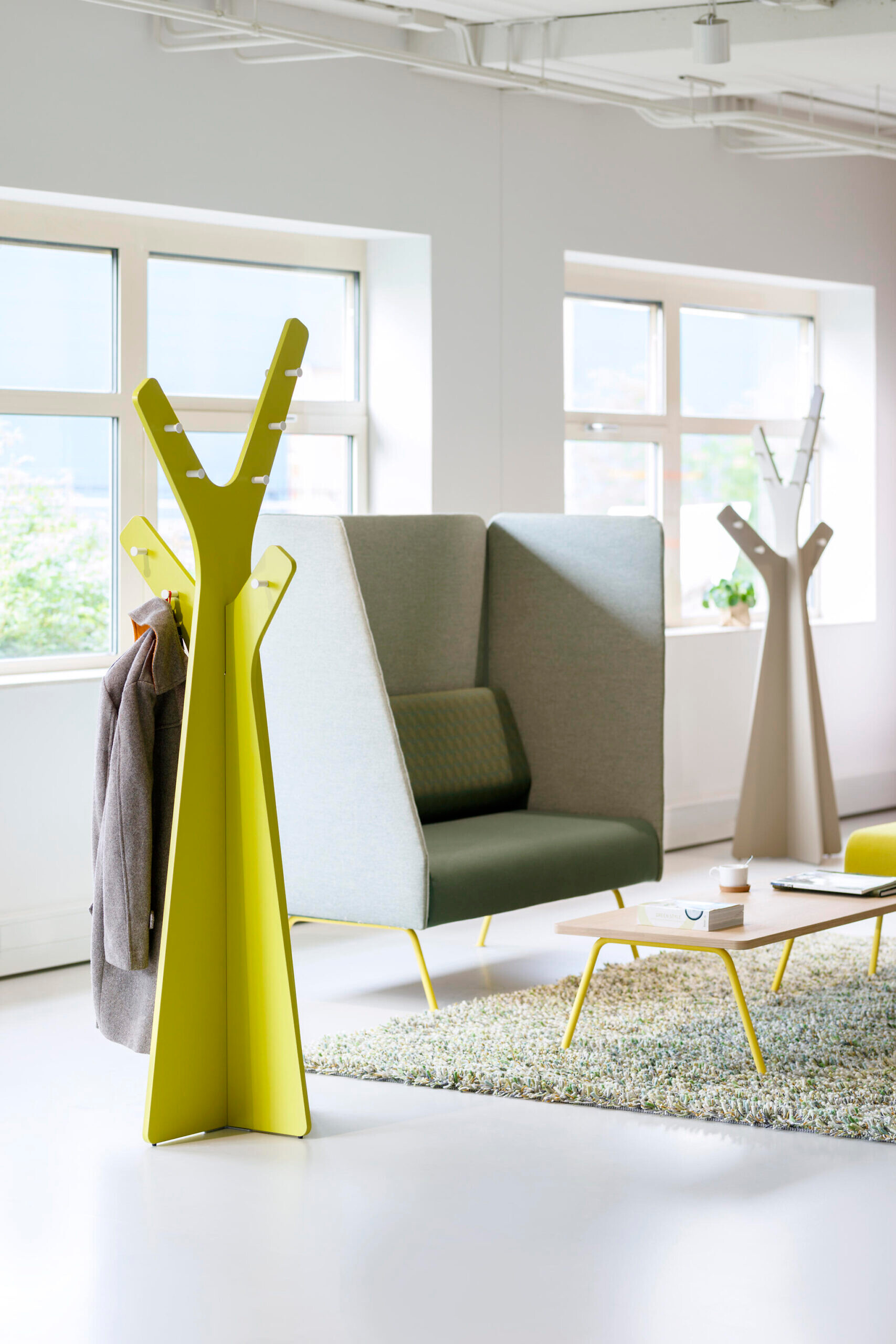 Gepolsterte Sitznische mit Sichtschutz und gelber Garderobe in heller Bürolandschaft