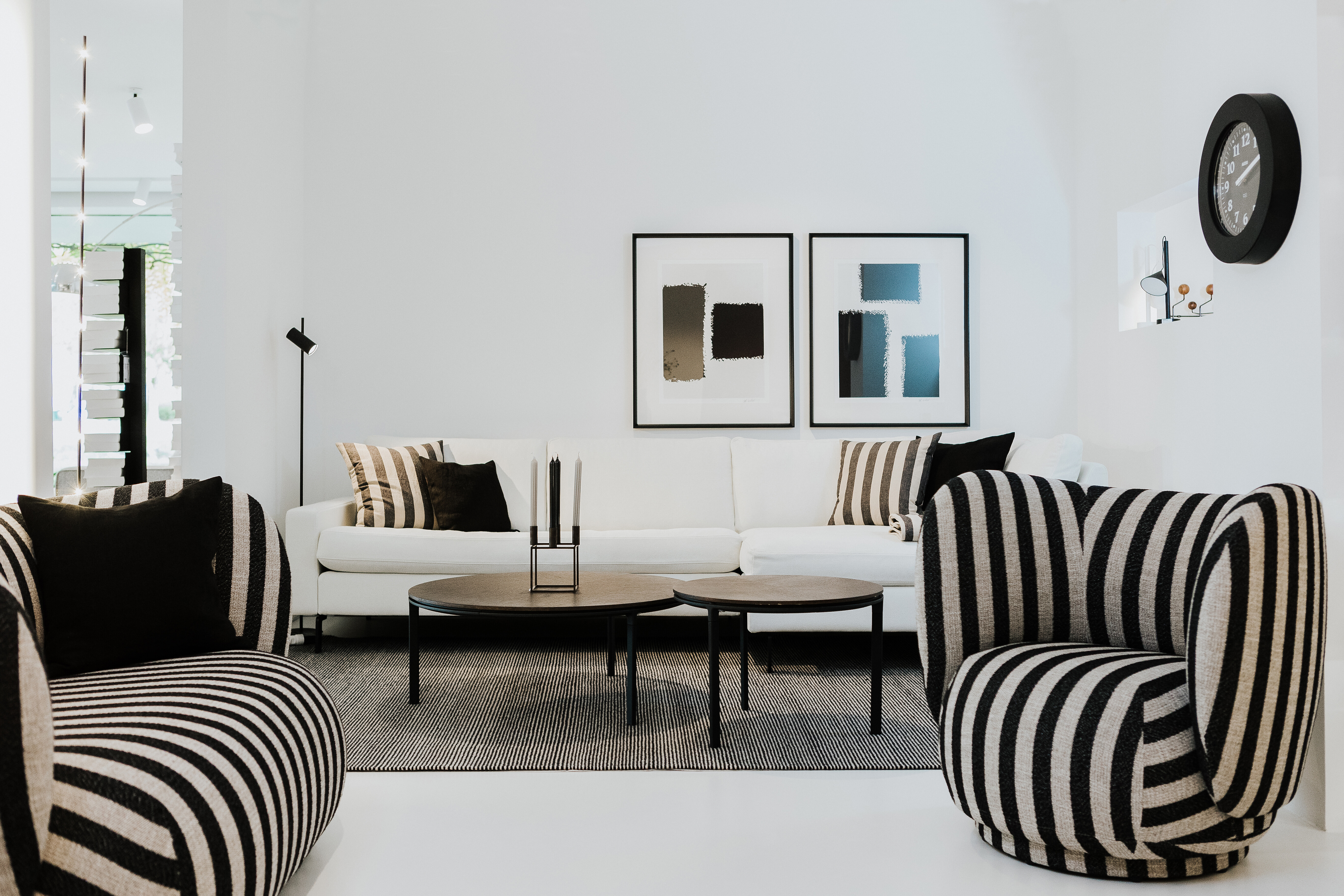 Zwei Vipp-Beistelltische vor weißem Sofa mit grafischen Sesseln in Schwarz-Weiß-Gestreift