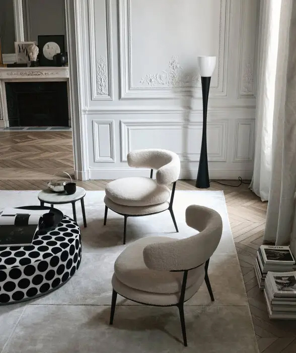 Zwei gepolsterte Rundsessel von B&B Italia auf hellem Teppich vor Stuckwand