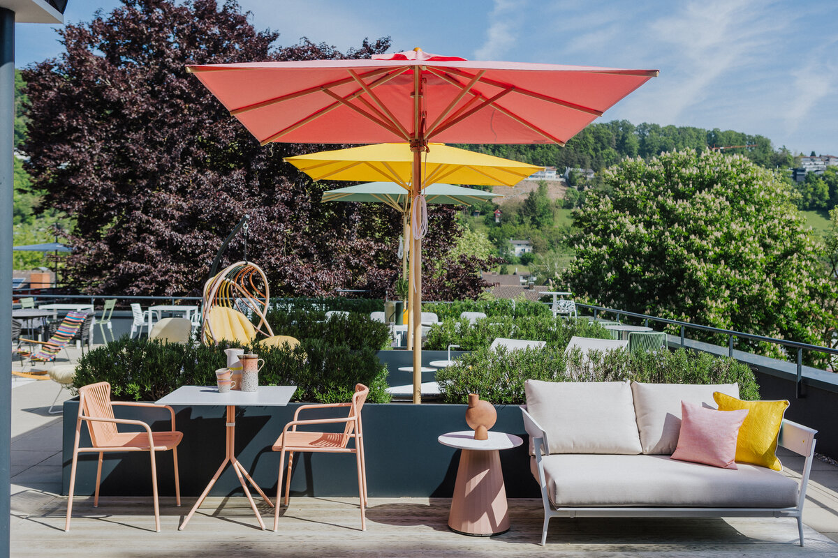 Gartenmöbel-Szenerie mit Sofa, Esstisch und Sonnenschirmen auf der Dachterrasse Tiengen bei Seipp Wohnen
