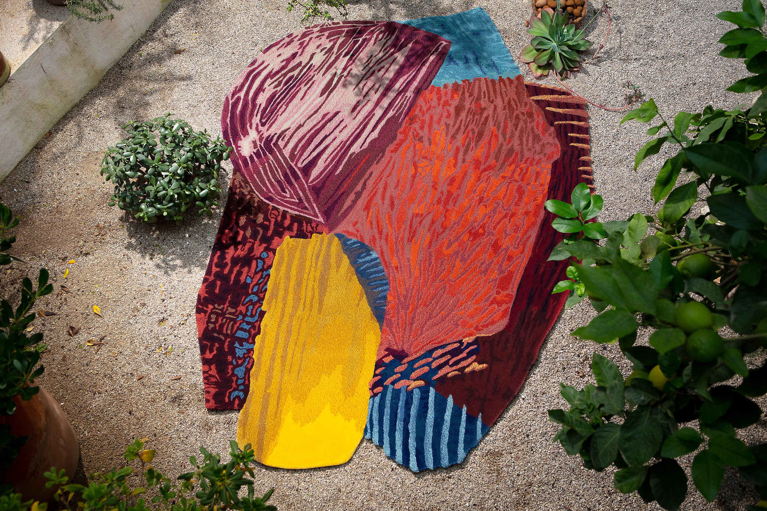 Bunter Teppich mit abstraktem Muster auf hellem Kiesboden im Außenbereich