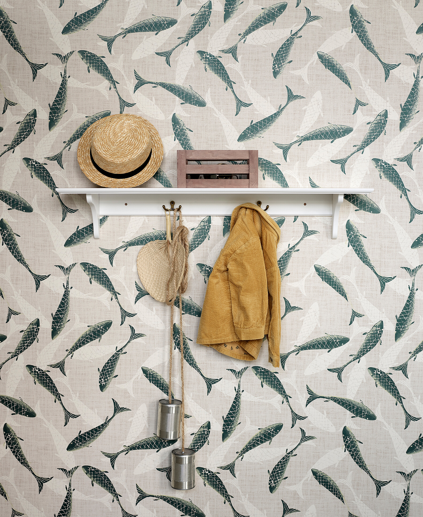 Weiße Wandgarderobe auf Fischmotiv-Tapete mit Strohhut, Tasche und Kinderspielzeug