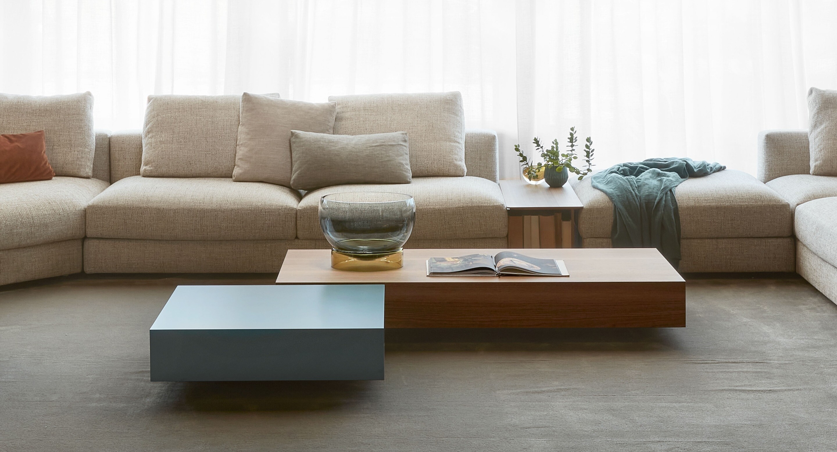 Modulares Sofa in hellem Beige mit kombiniertem Couchtisch aus Holz und farbig lackiertem Volumen