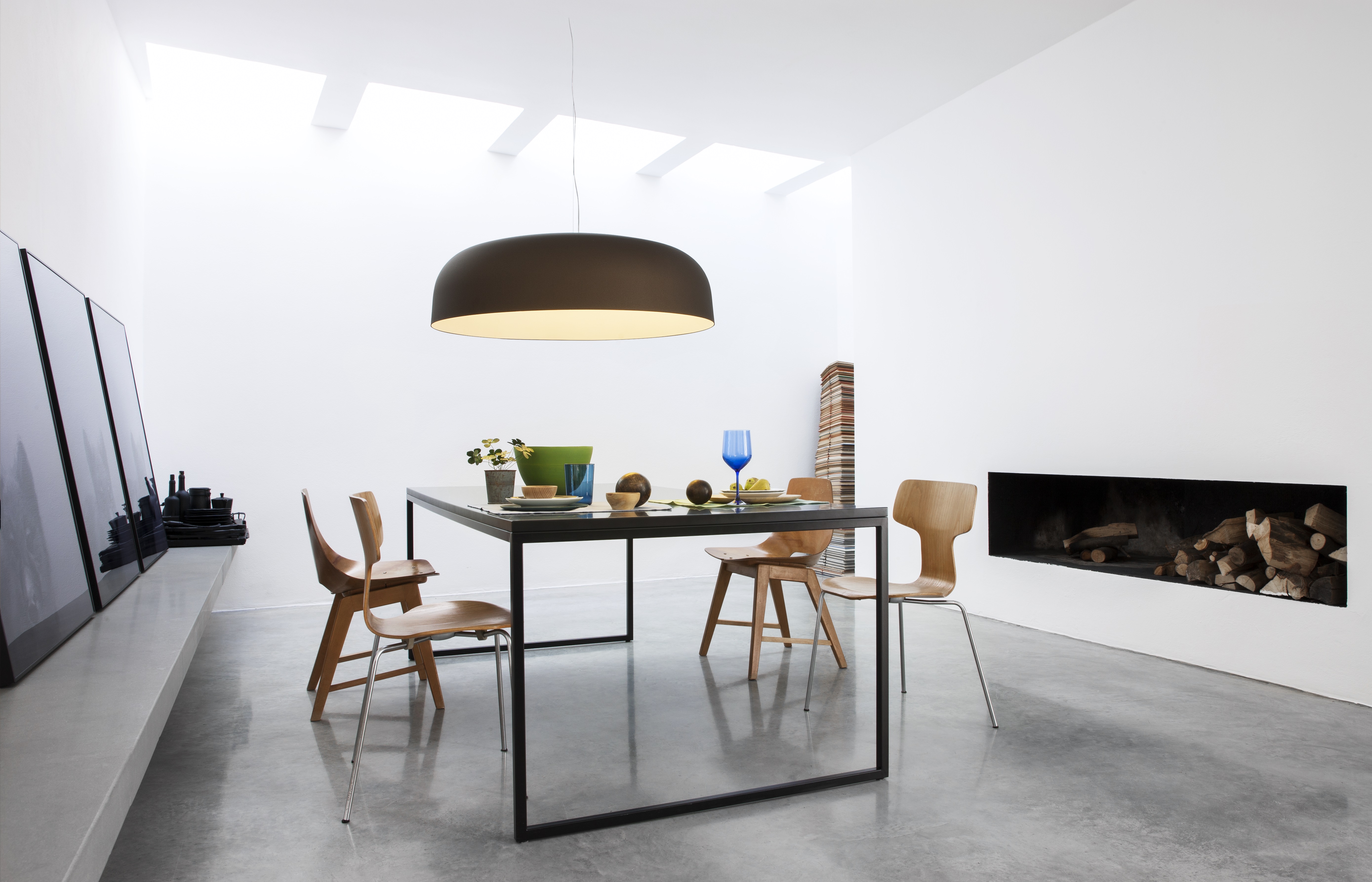Pendelleuchte Oluce Canopy über modernem Esstisch mit vier Holzstühlen im Raum