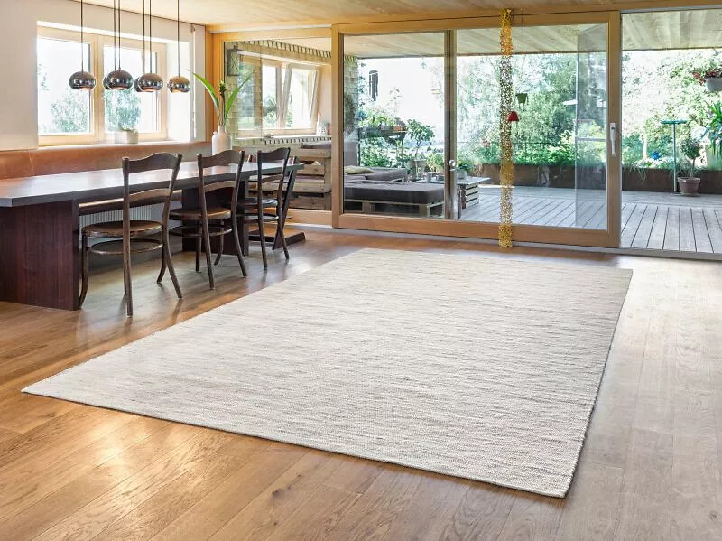 Essbereich mit großem weißen Teppich auf Holzfußboden vor bodentiefen Fenstern