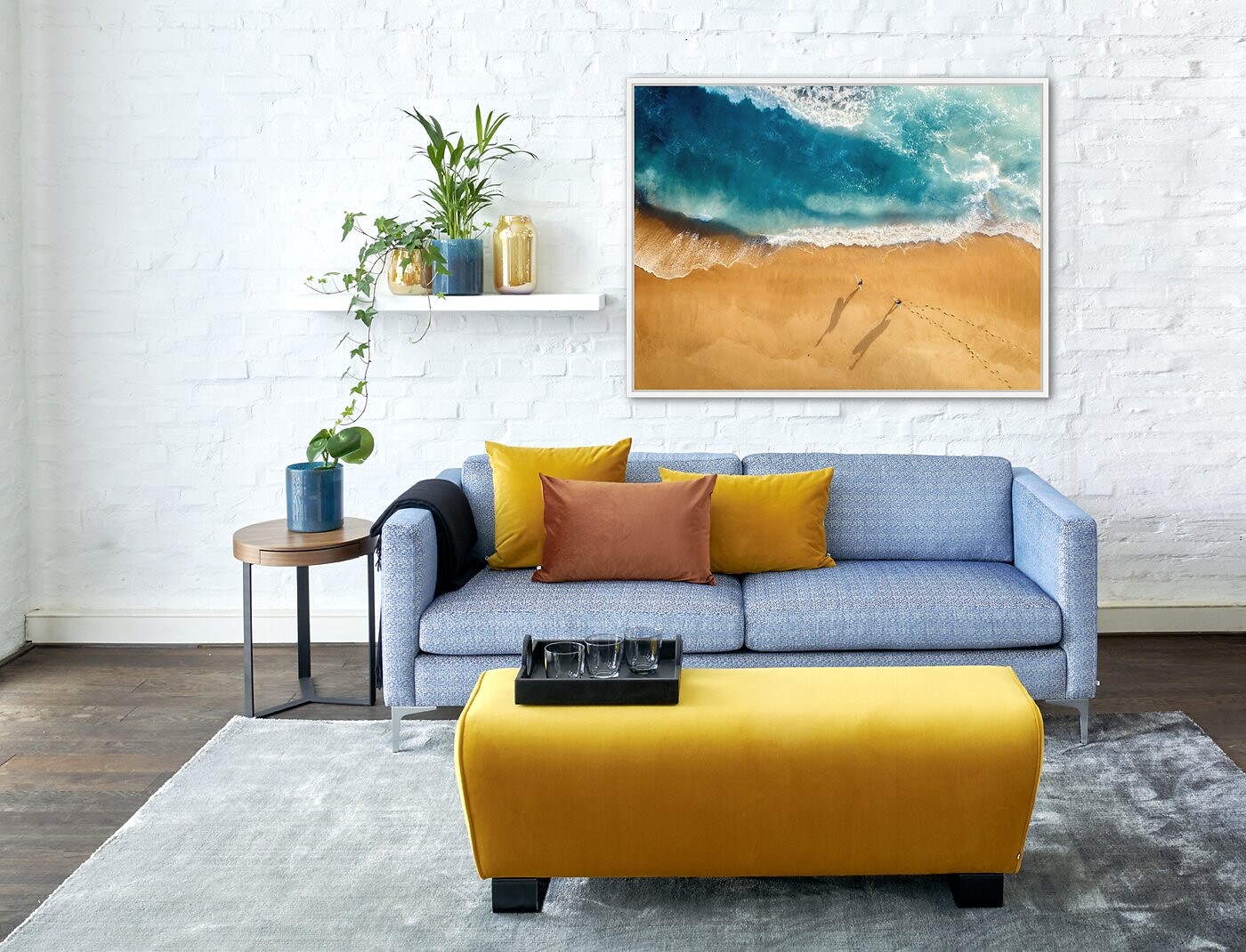 Modernes Sofa mit bunten Kissen vor Kunstwerk mit Meeresmotiv und Wandregal