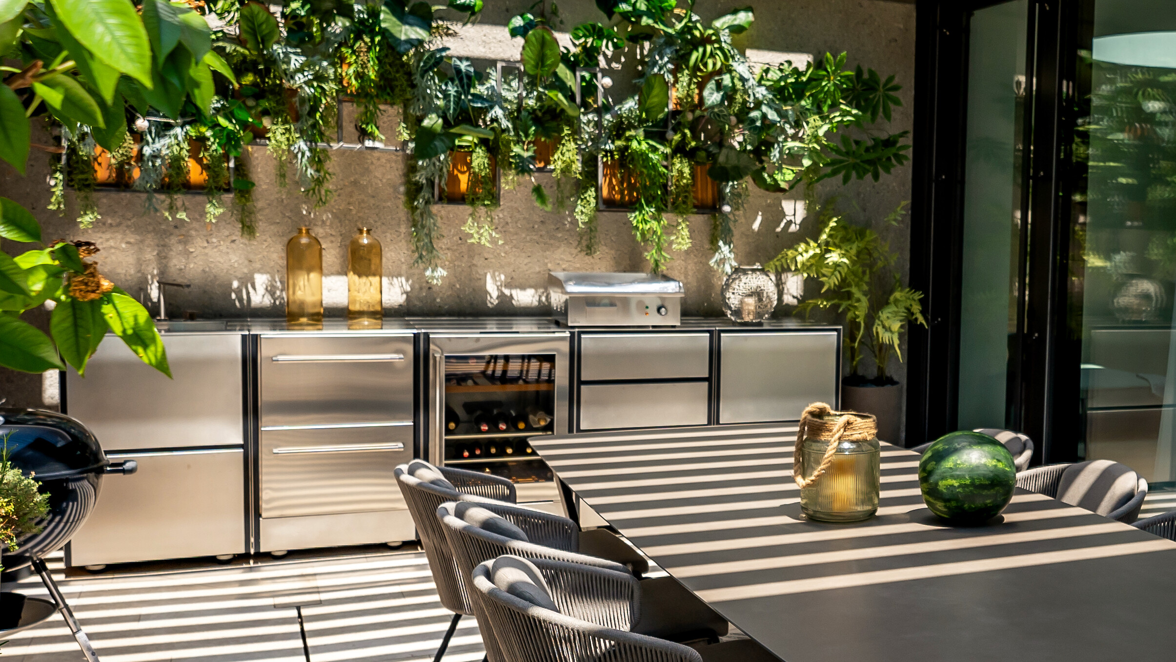 Vollausgestattete Outdoor-Küche aus Edelstahl mit Weinlager und Pflanzdekor
