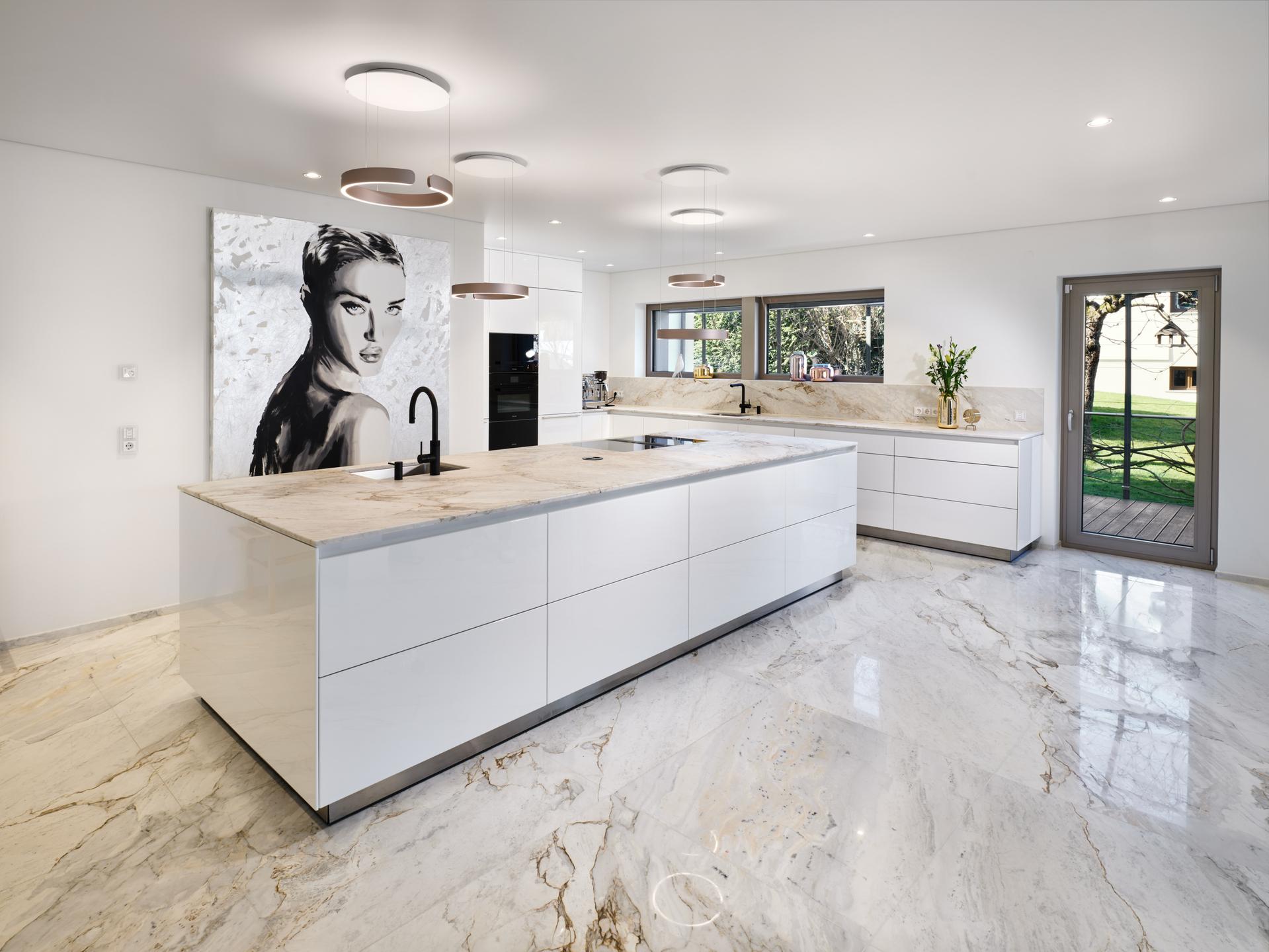 Großzügige bulthaup b3 Küche mit Hochglanzfronten, heller Steinfläche und Kunstmotiv an der Wand.