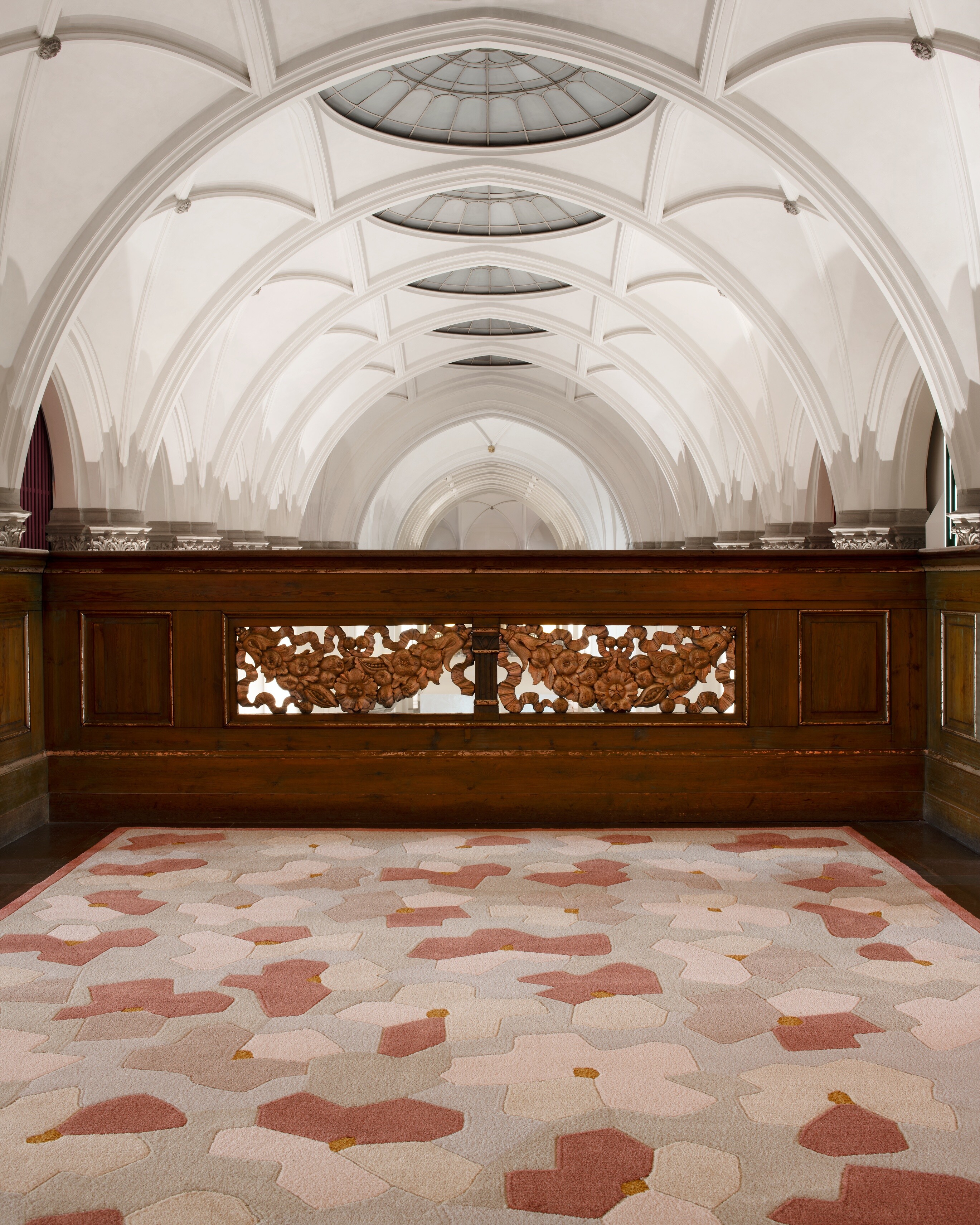 Kasthall-Teppich in Rosé- und Sandtönen vor aufwendig gestalteter Holzbrüstung