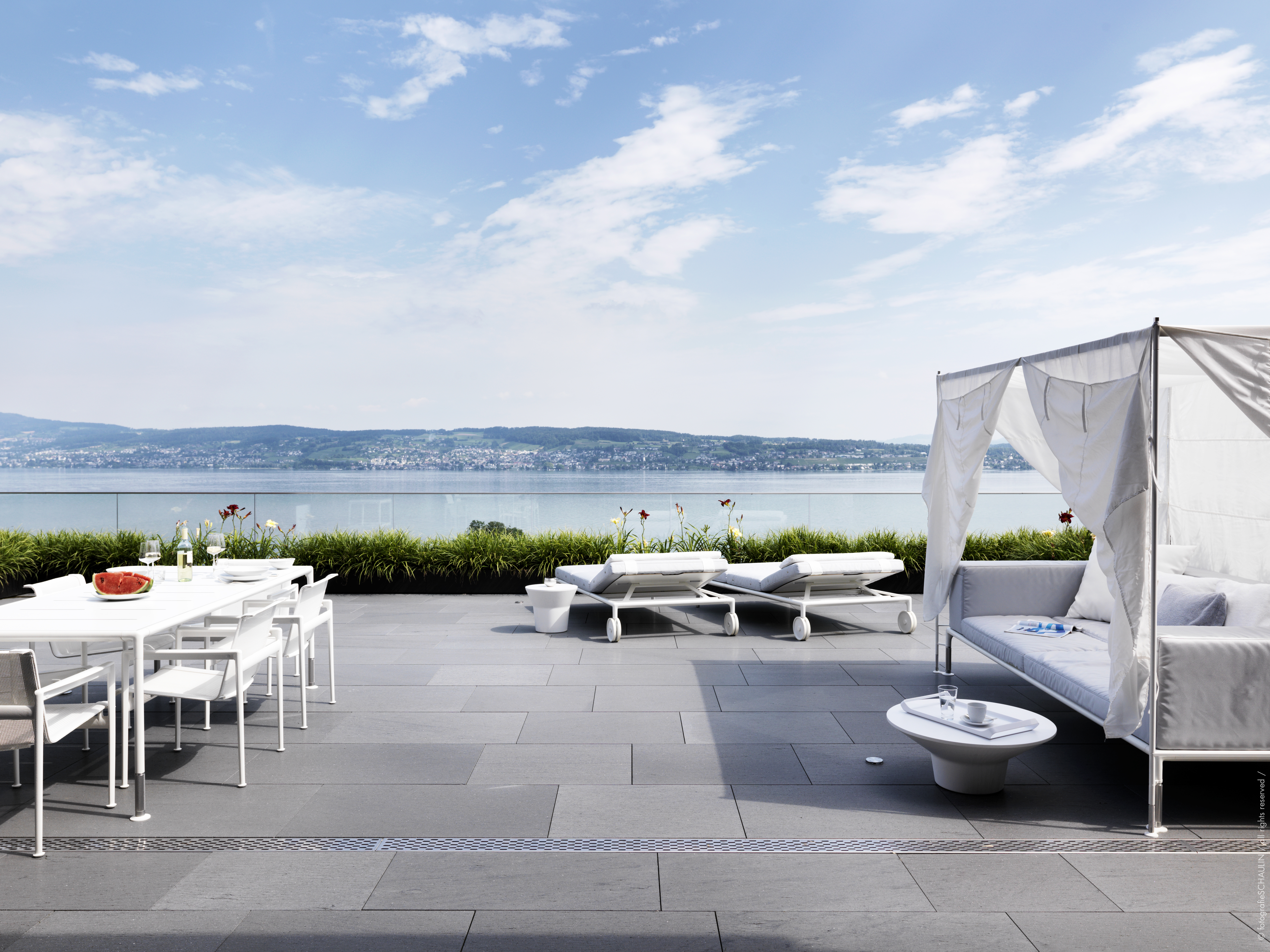 Moderne Terrasse mit weißer Outdoor-Lounge und Essbereich – mit Blick über den Zürichsee.