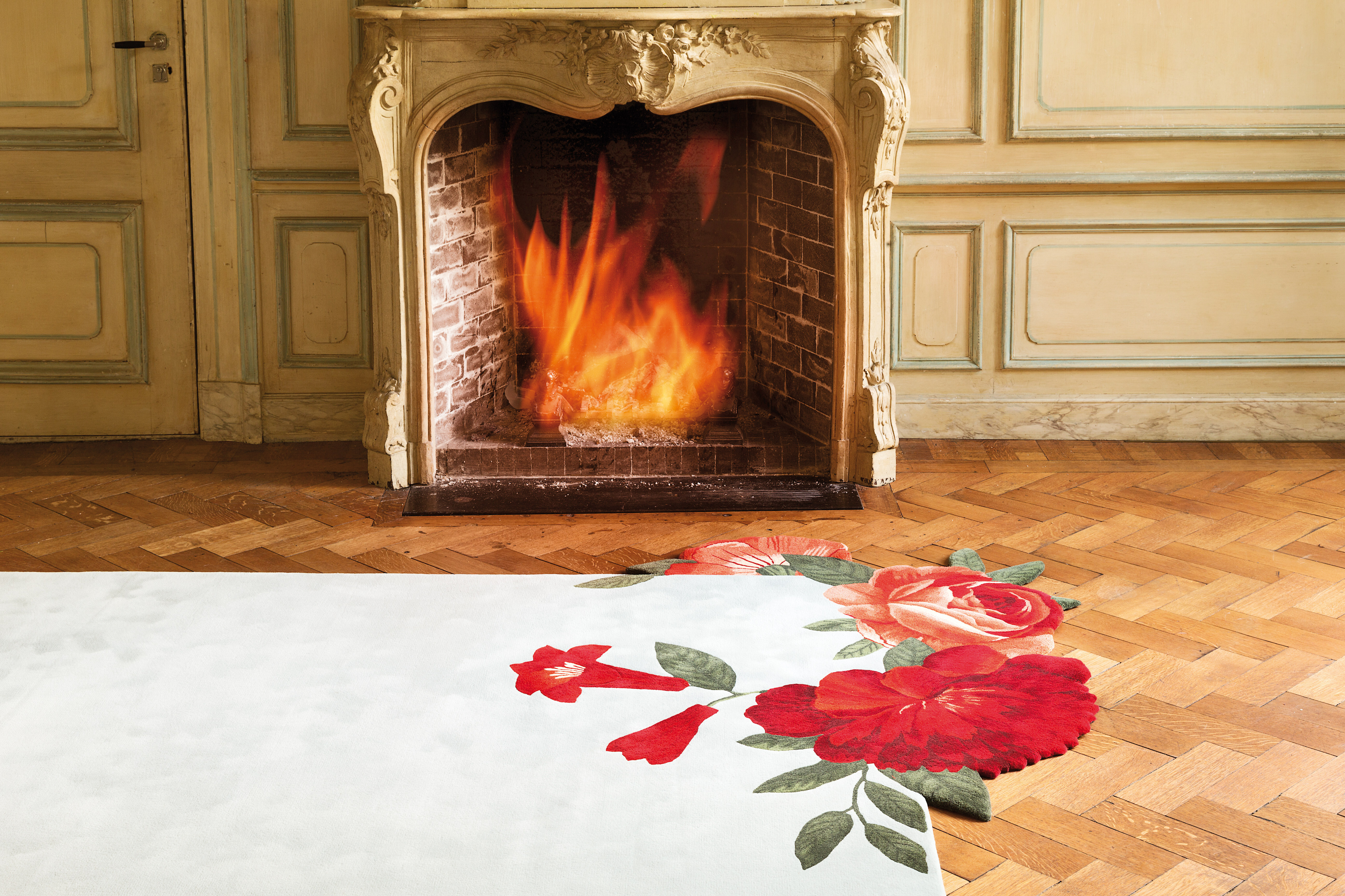 Floraler Teppich in Weiß mit roten Blütenmotiven vor Kamin in Altbau