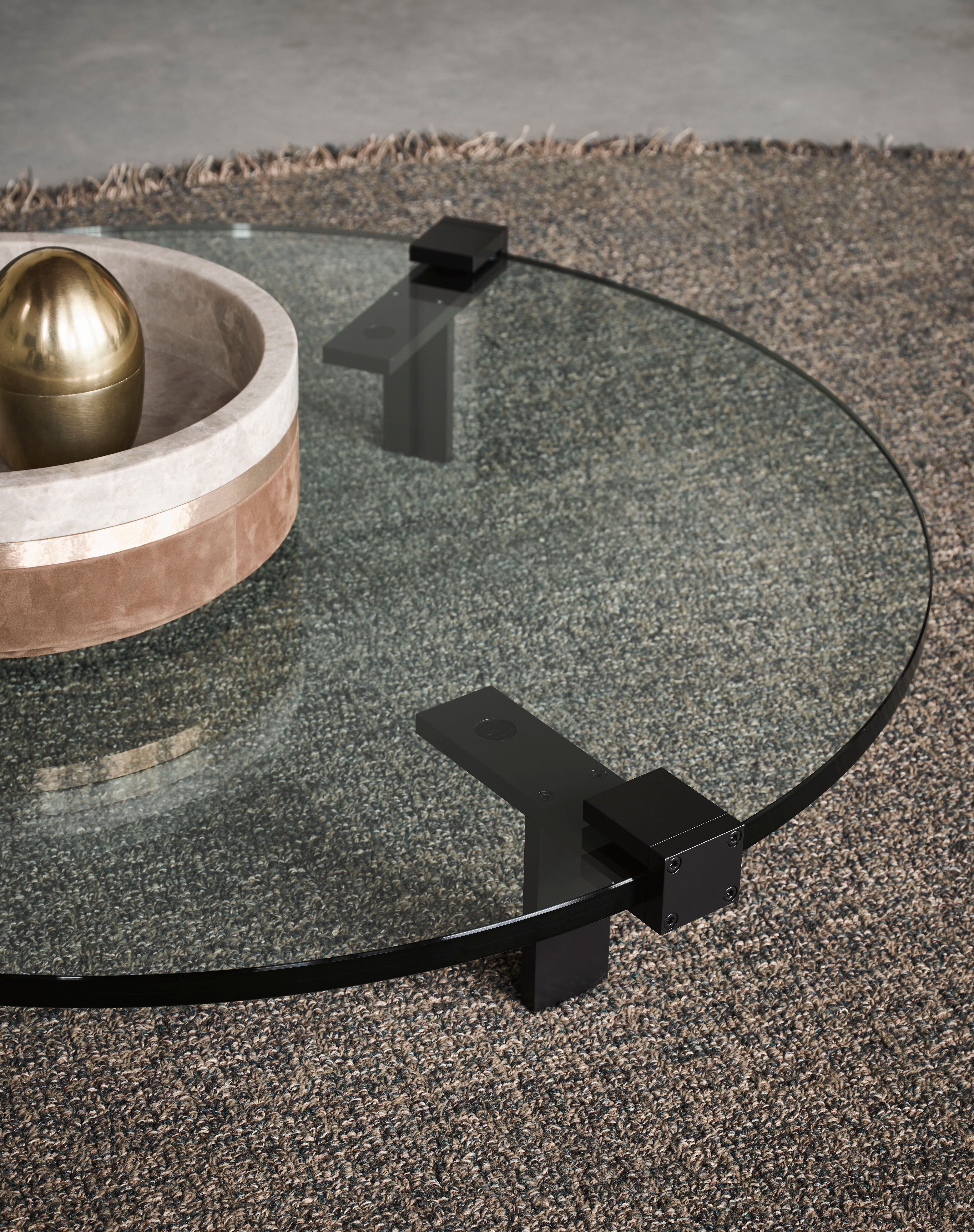 Runder Glastisch mit schwarzem Gestell auf strukturreichem Teppich in Naturtönen