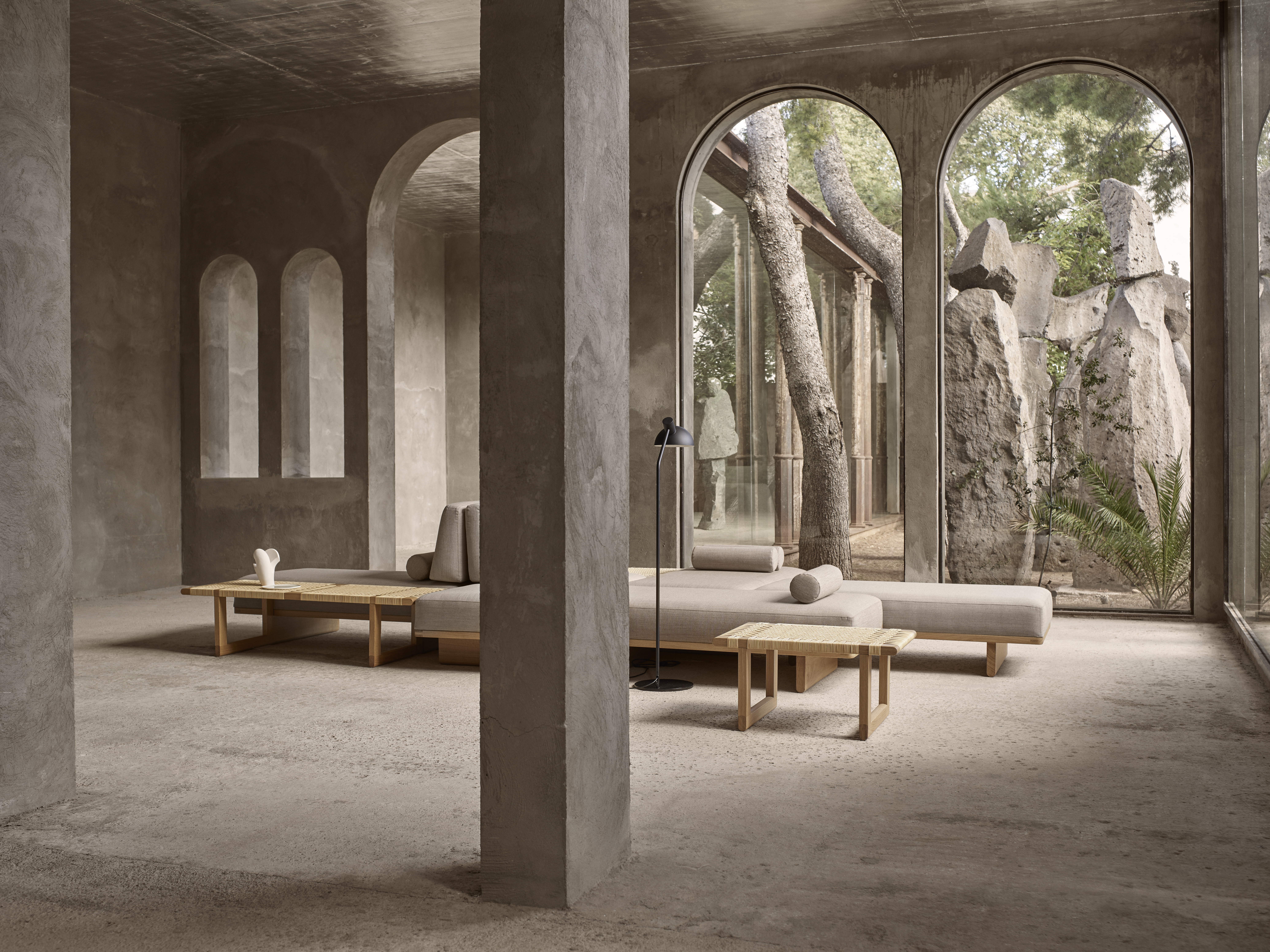 Modulares Sofa mit hellem Bezug in offenem Raum mit Rundbögen und Steinboden