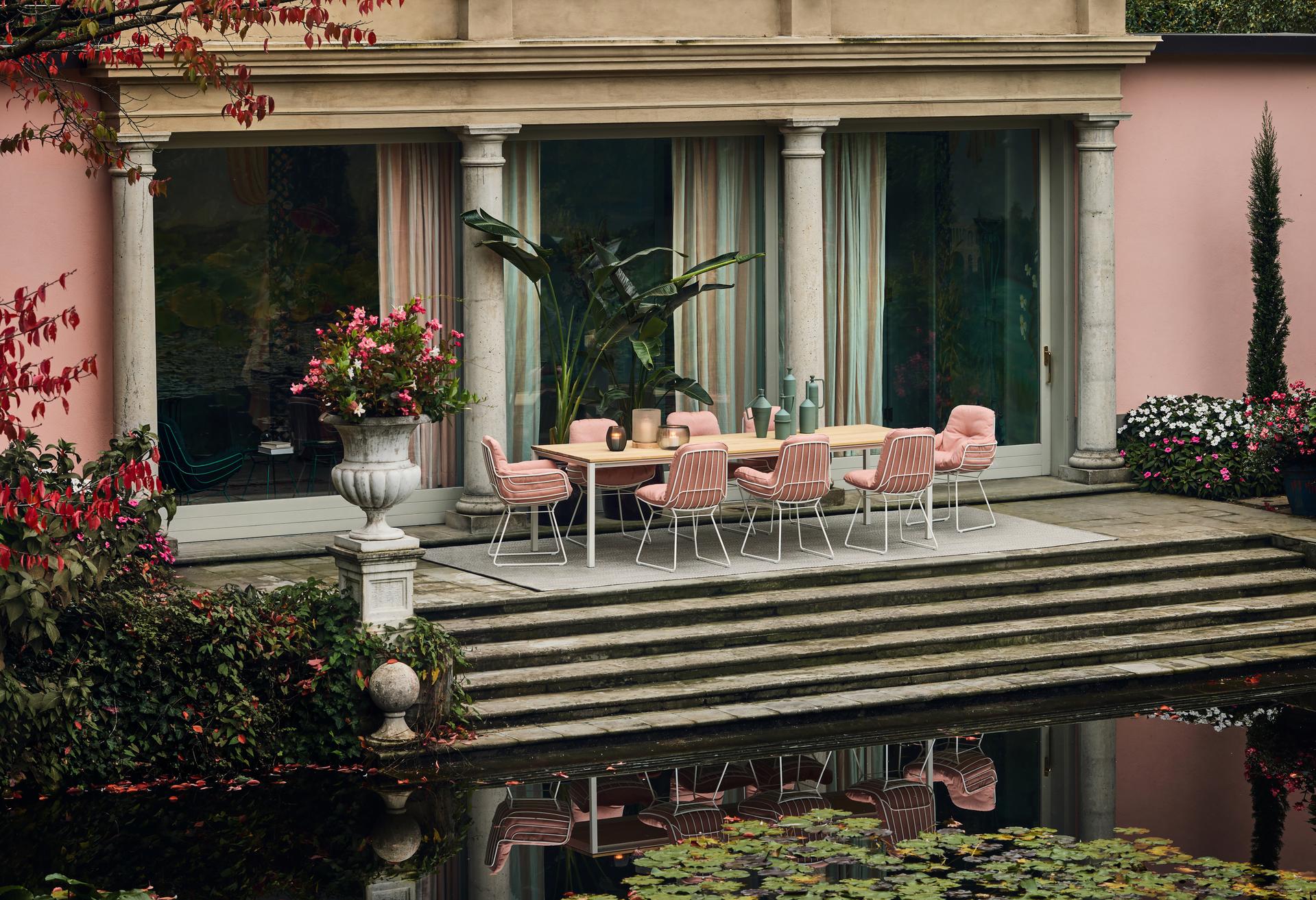 Freifrau Stühle in Rosé rund um einen Esstisch auf einer Terrasse mit Seerosenteich