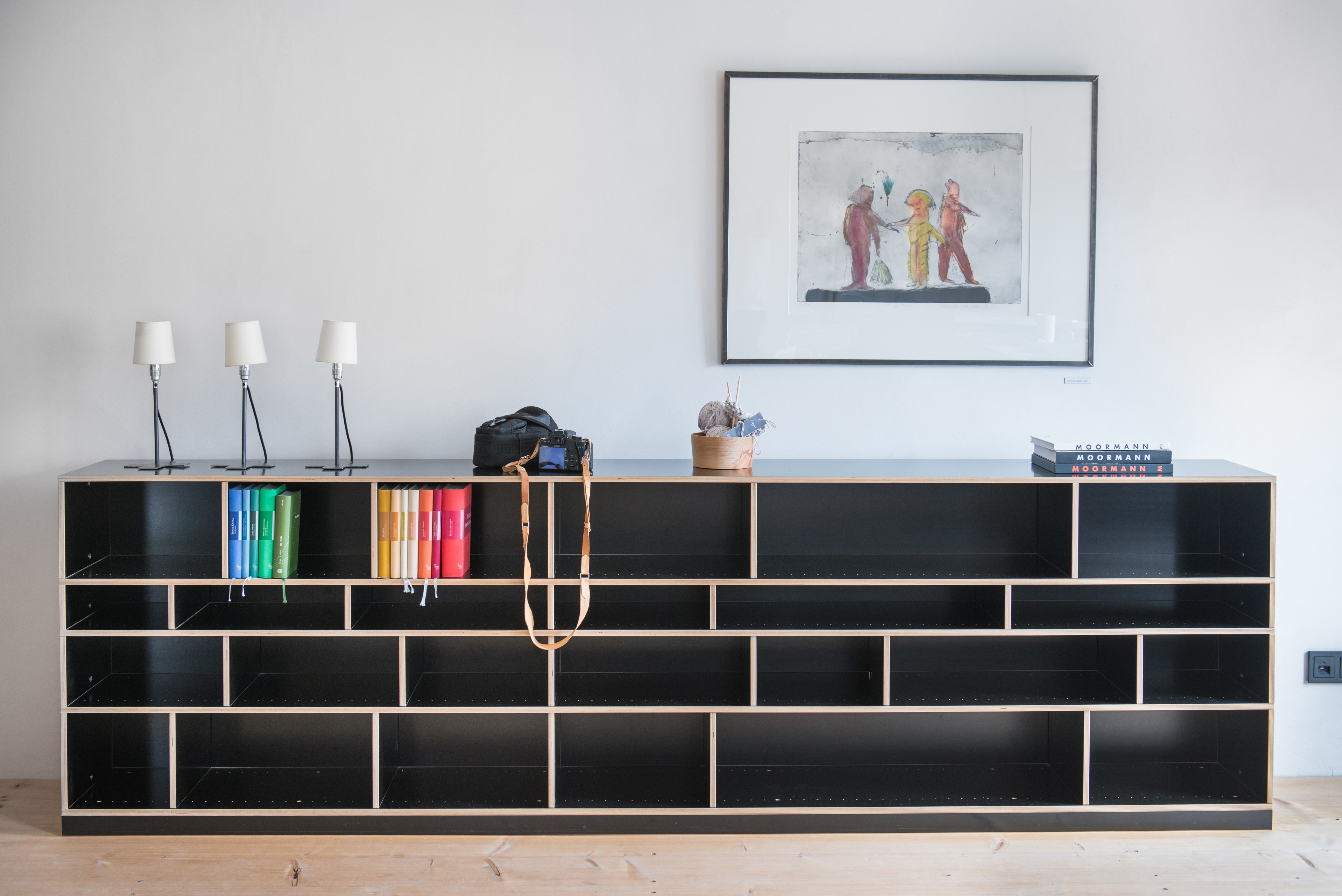 Schwarzes Regal von Moormann mit farbigen Büchern, Kamera und Dekoobjekten