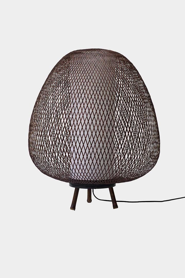 Tischleuchte aus schwarzem Bambusgeflecht mit sichtbarem Innenzylinder, auf drei kurzen Füßen stehend.