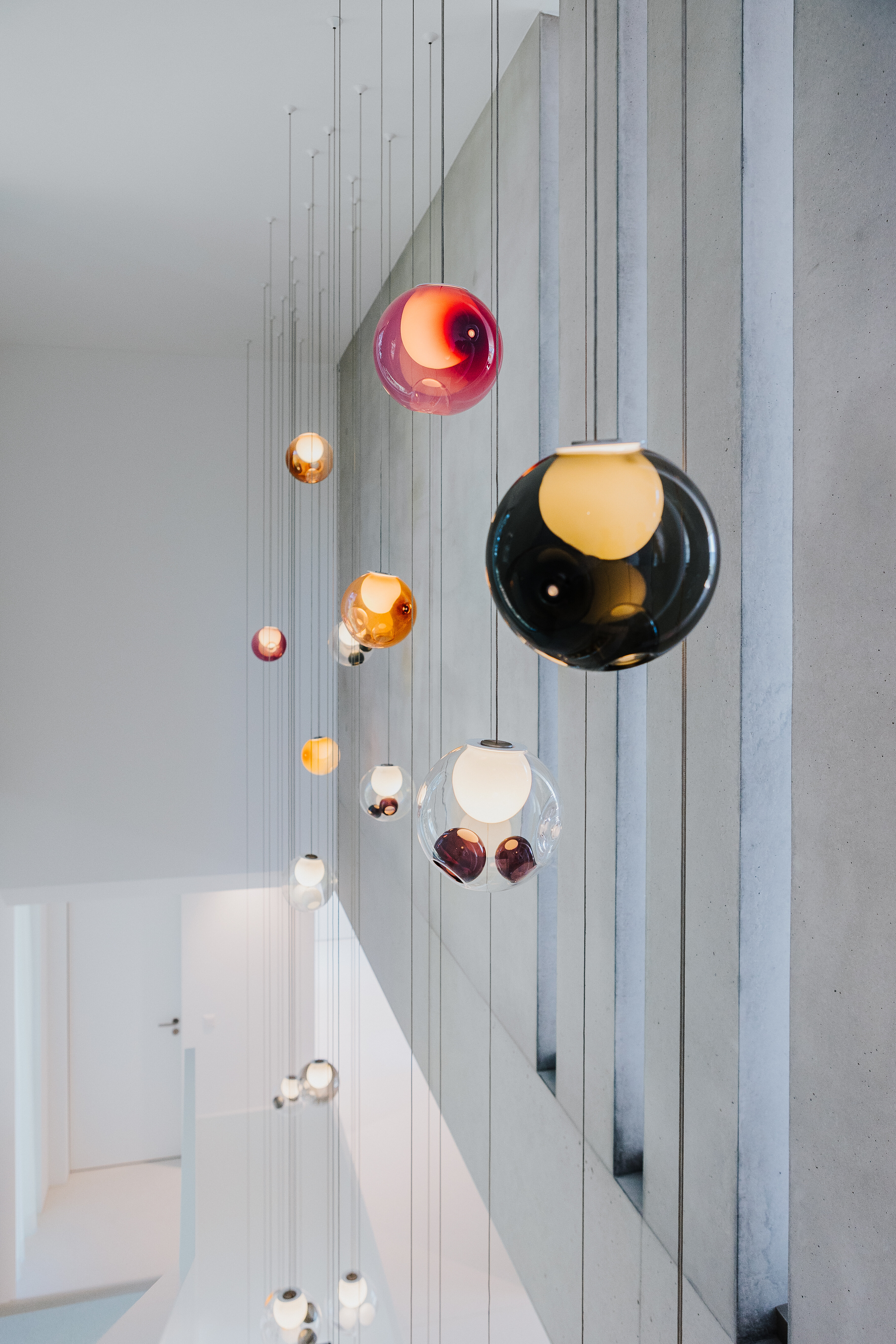 Pendelleuchte mit farbigen Glaskugeln in Treppenhaus-Architektur