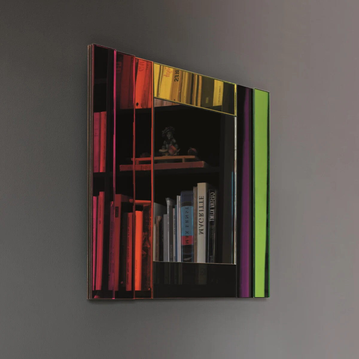 Spiegel mit farbig getöntem Glasrahmen und sichtbarem Bücherregal im Spiegelbild.