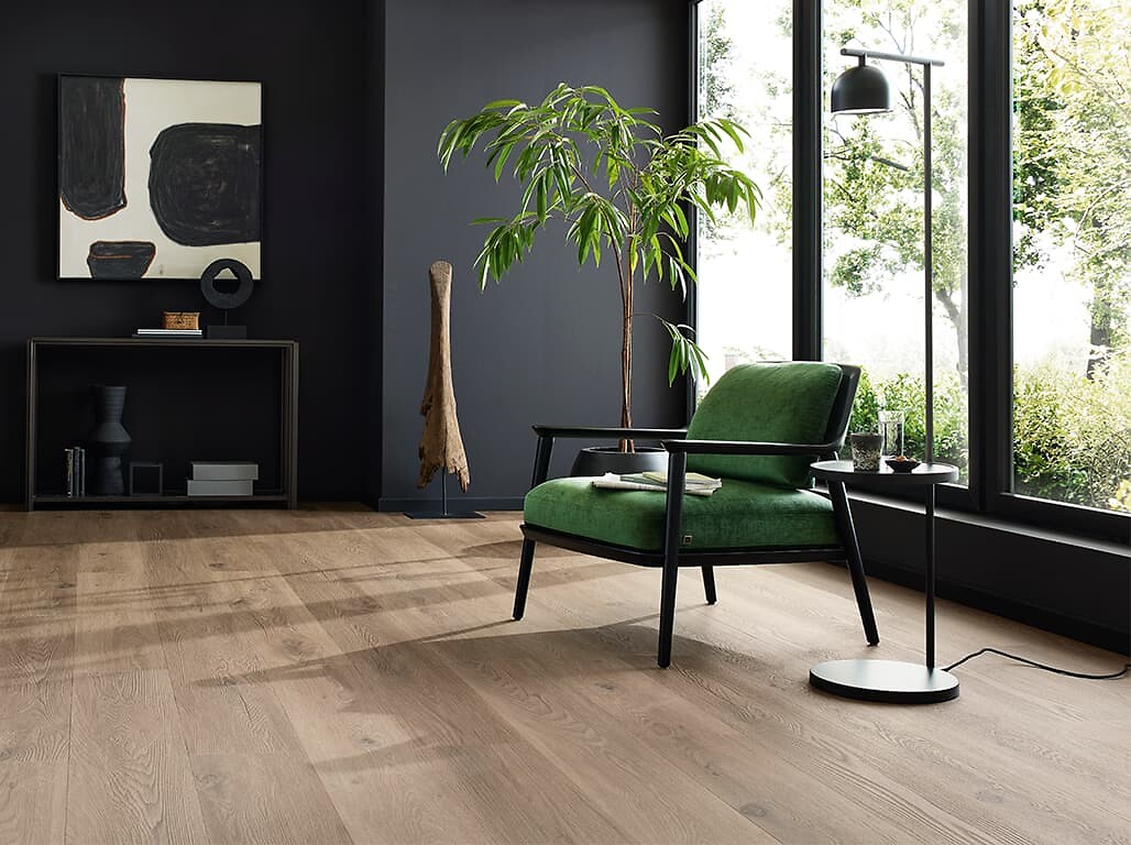 Wohnbereich mit grünem Loungesessel auf geöltem Parkettboden vor Fensterfront
