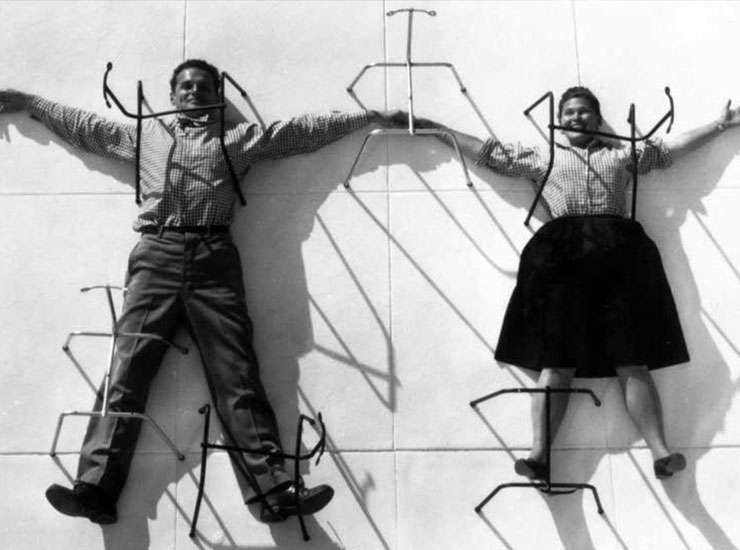 Charles und Ray Eames auf einem ikonischen Foto mit Stuhlgestellen – ein Sinnbild ihres visionären Designs.