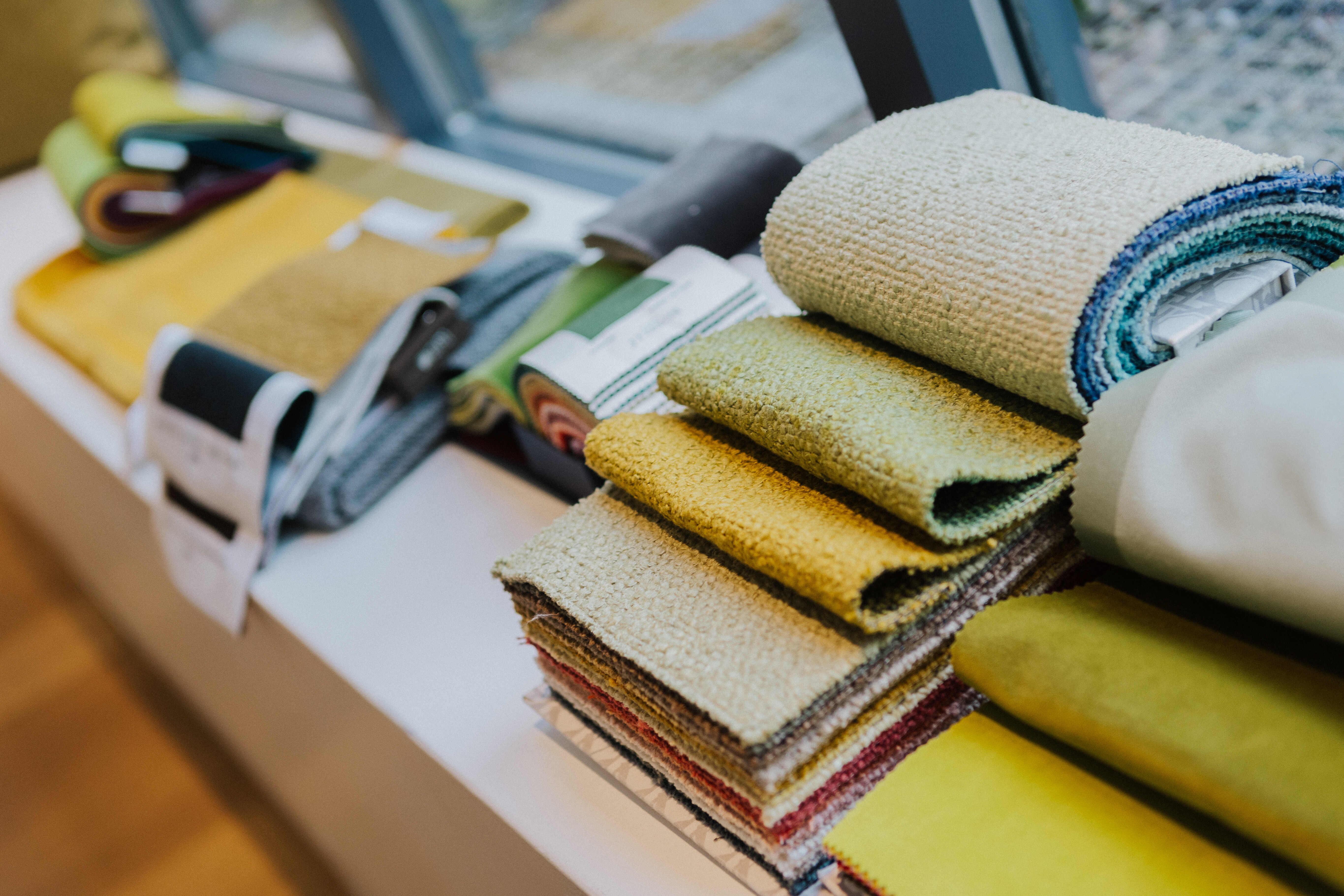 Stoffmuster in verschiedenen Gelb-, Grün- und Naturtönen, ausgebreitet auf einer Fensterbank