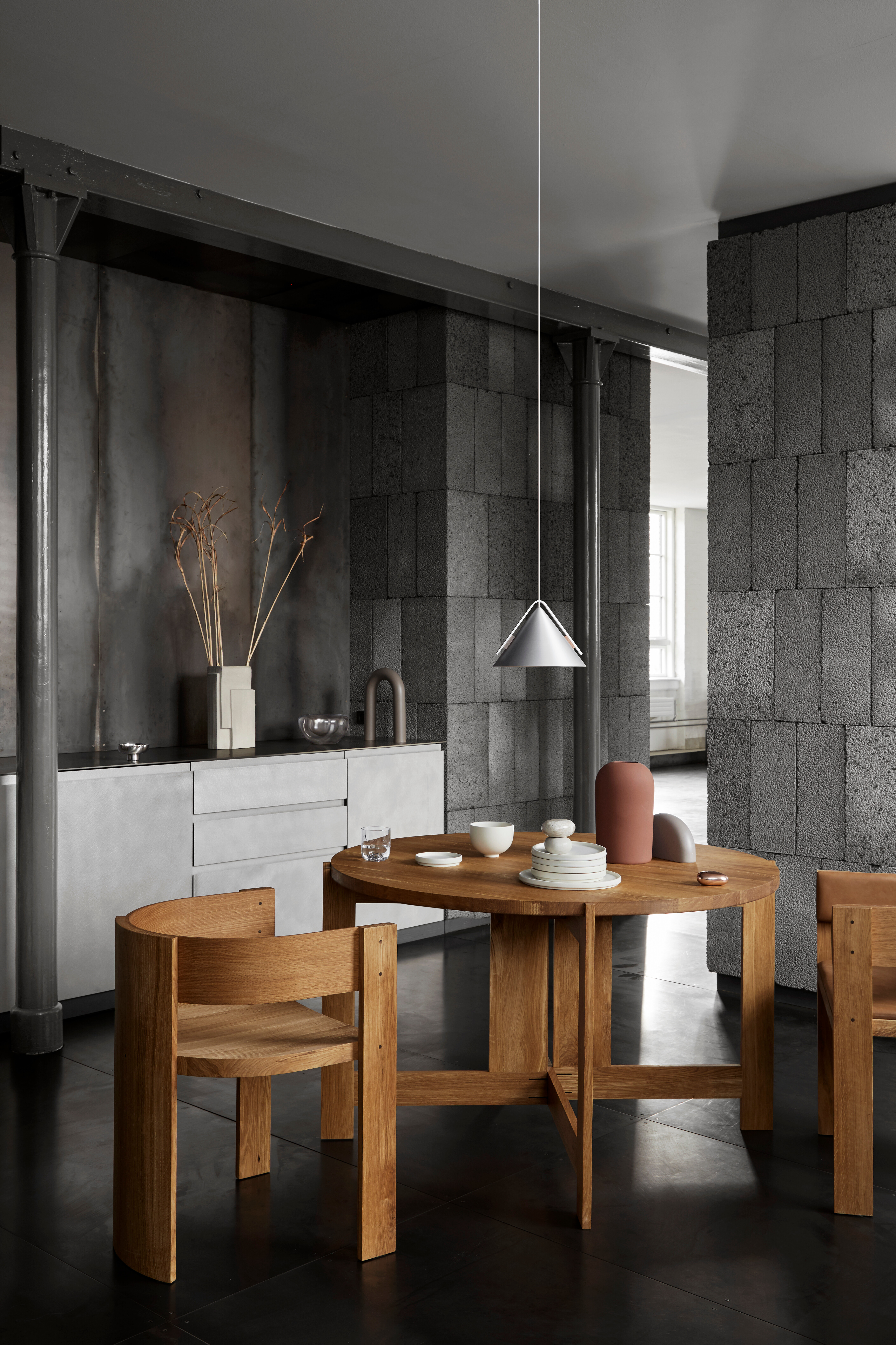 Runder Holztisch mit passenden Stühlen in Küche mit Beton- und Stahlakzenten