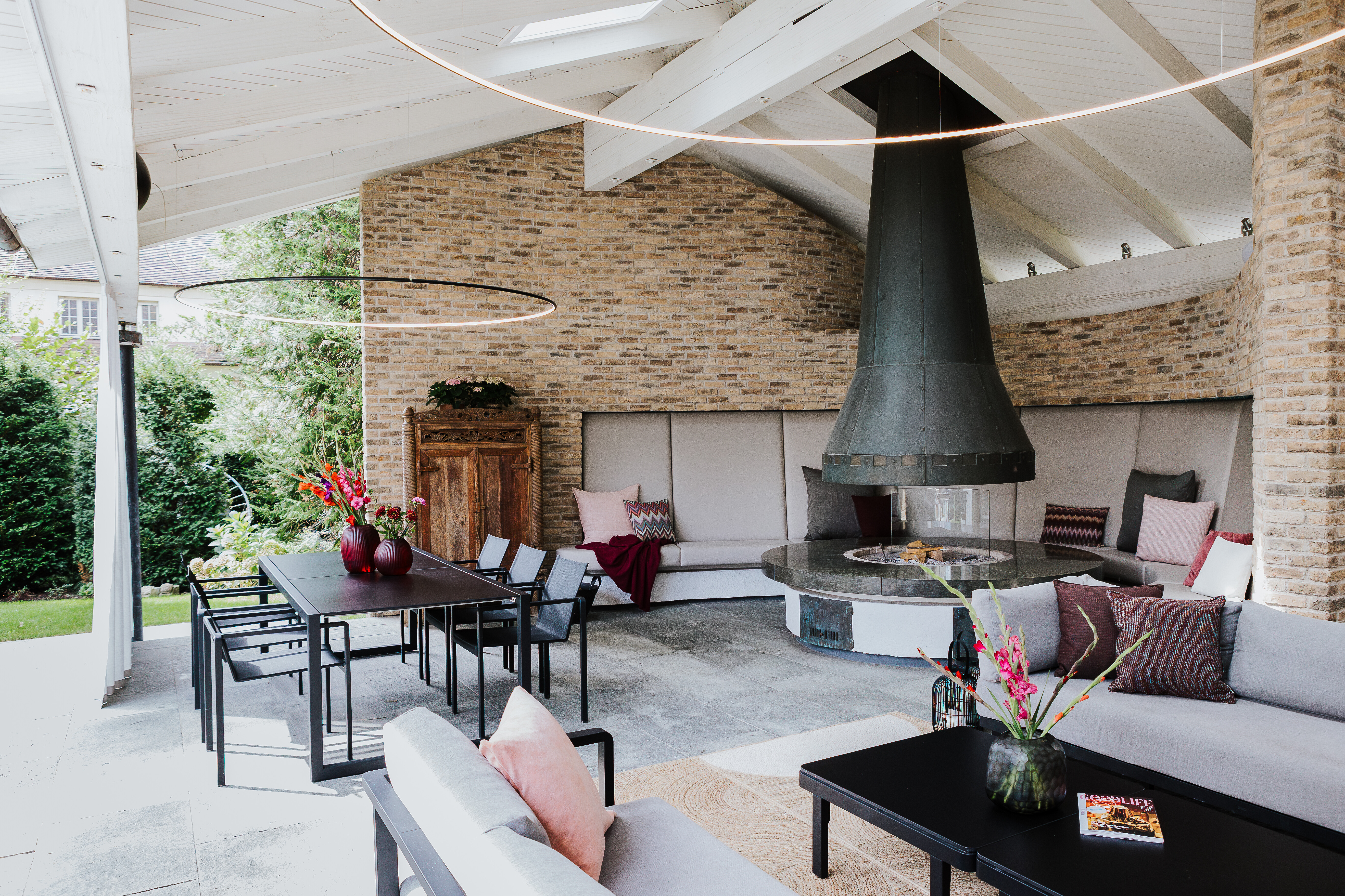 Überdachte Terrasse mit offenem Kamin, Sofas und Esstisch – Einrichtungskonzept von Seipp Wohnen