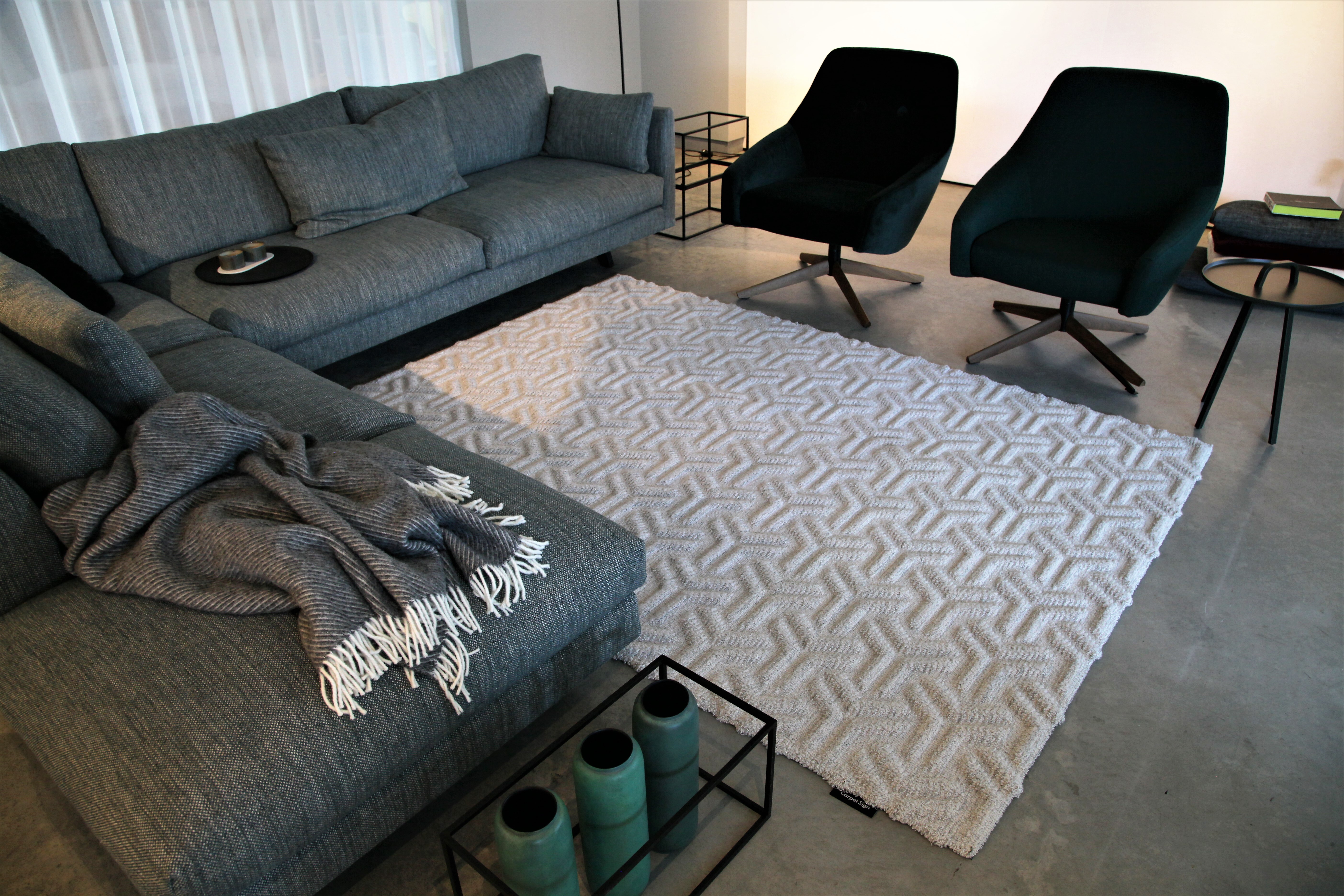 Heller Teppich mit geometrischem Muster im Wohnbereich mit grauem Sofa und Sesseln